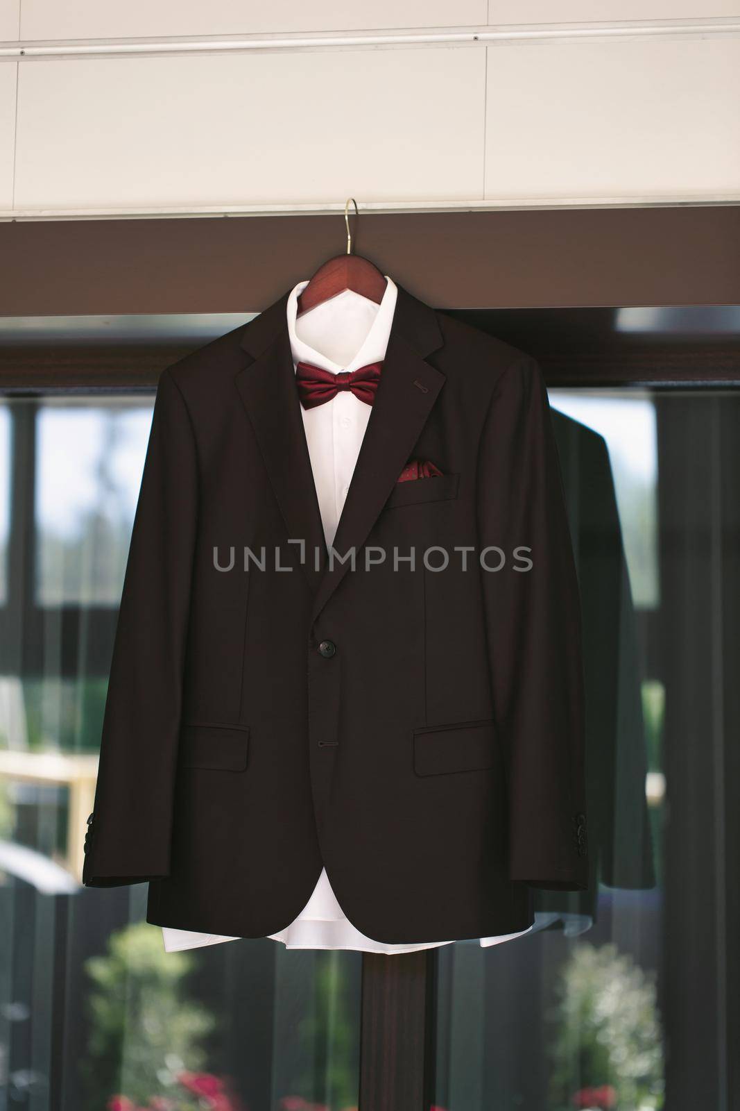 Suit jacket hanging on a hanger with a boutonniere in place.