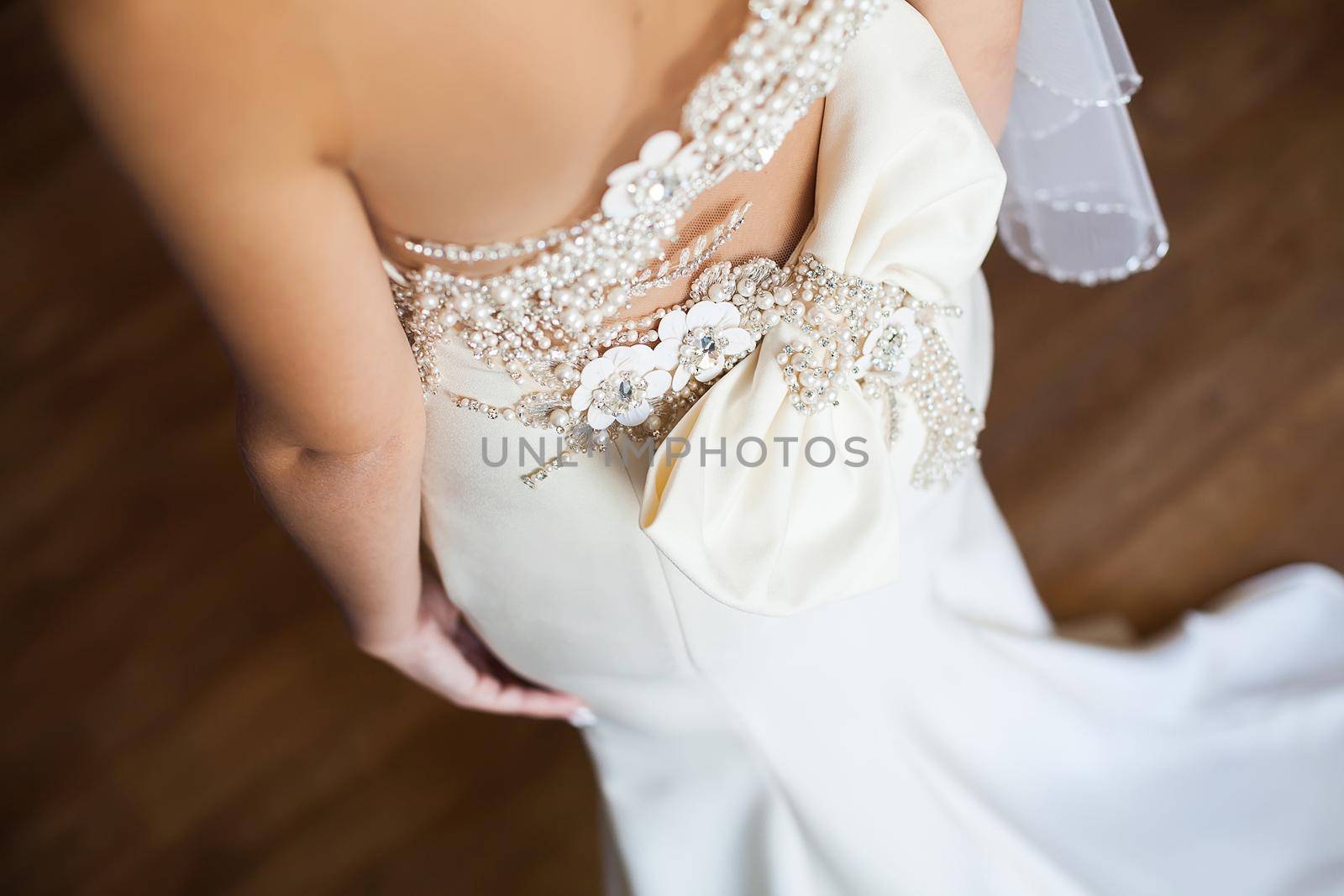 Bridesmaid makes bow-knot on the back of brides wedding dress. by StudioPeace