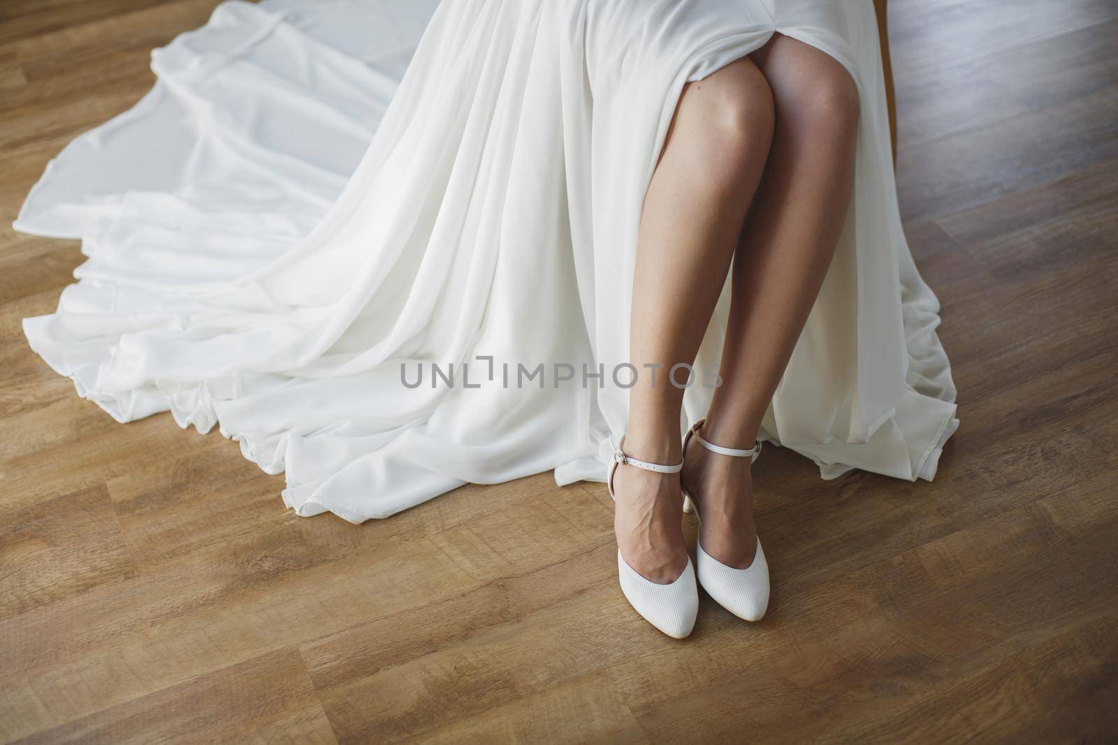 bride puts on white shoes on feet. by StudioPeace