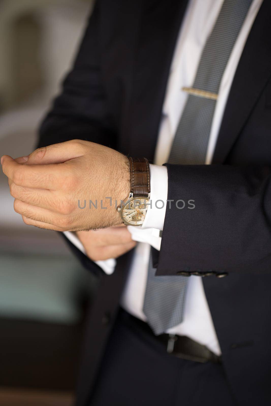 A man in a suit puts a watch on his hand. by StudioPeace