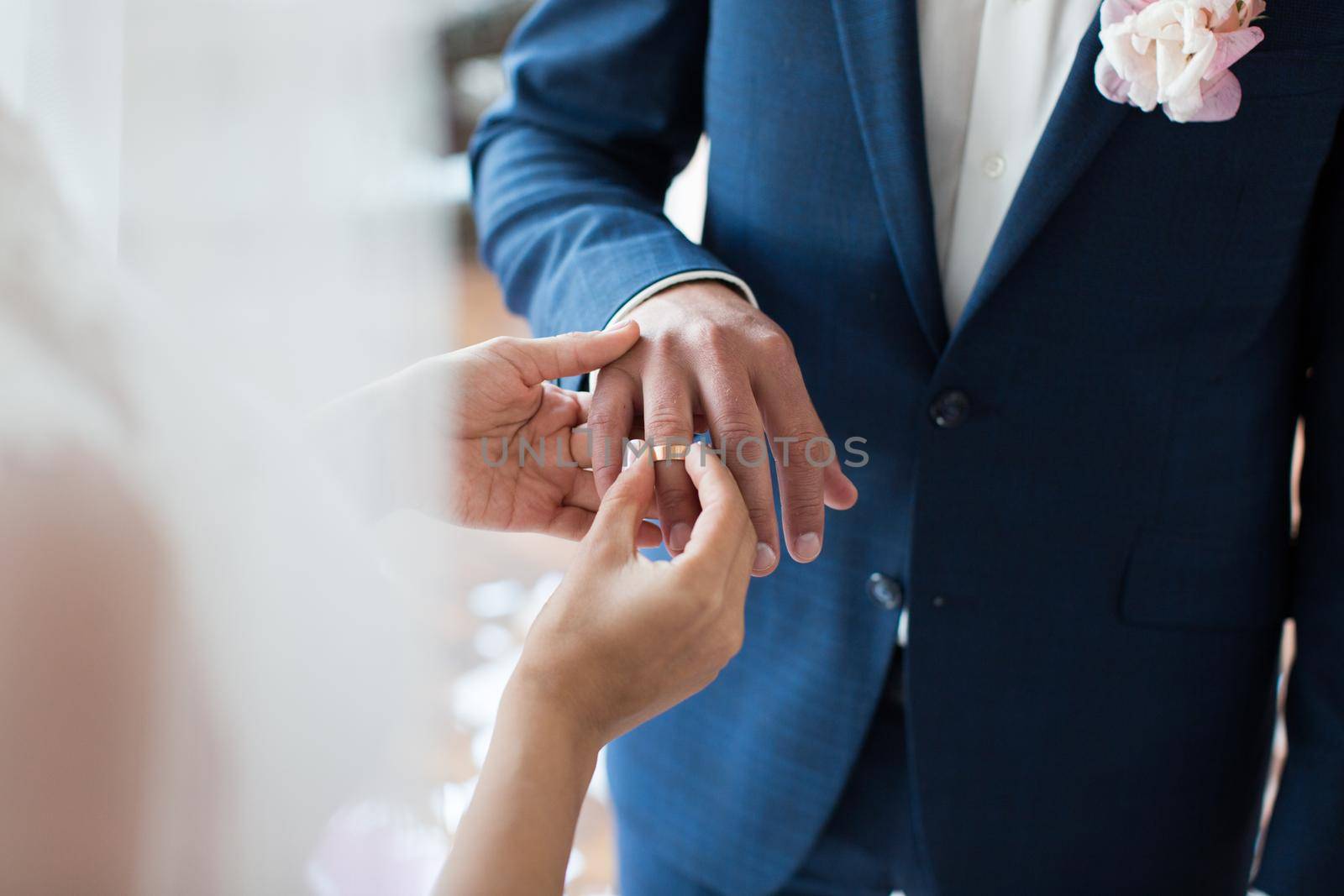 The bride puts a ring on the bride's finger during the wedding ceremony