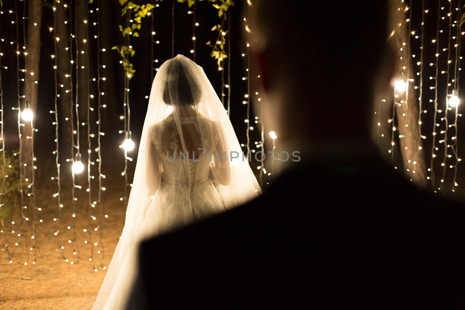 Wedding ceremony night. Meeting of the newlyweds, the bride and groom in the coniferous pine forest of candles and light bulbs by StudioPeace