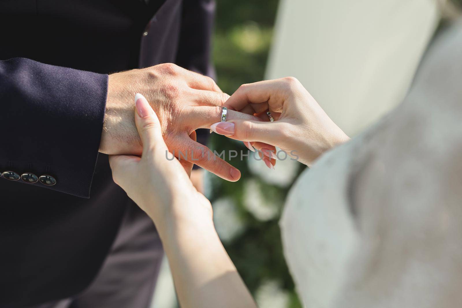 The bride puts a ring on the groom's finger in close-up. by StudioPeace