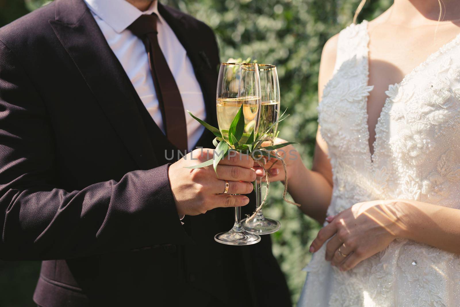 The bride and groom hold crystal glasses filled with champagne
