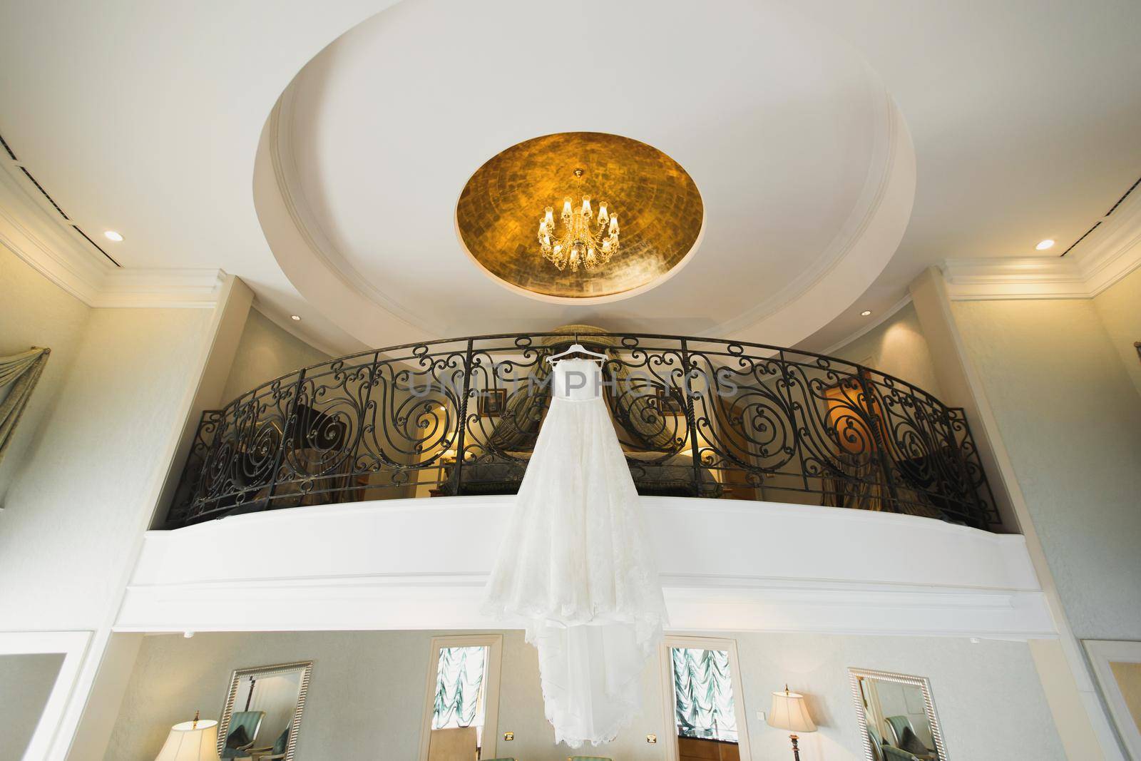White wedding dress hangs on the balcony of a hotel room
