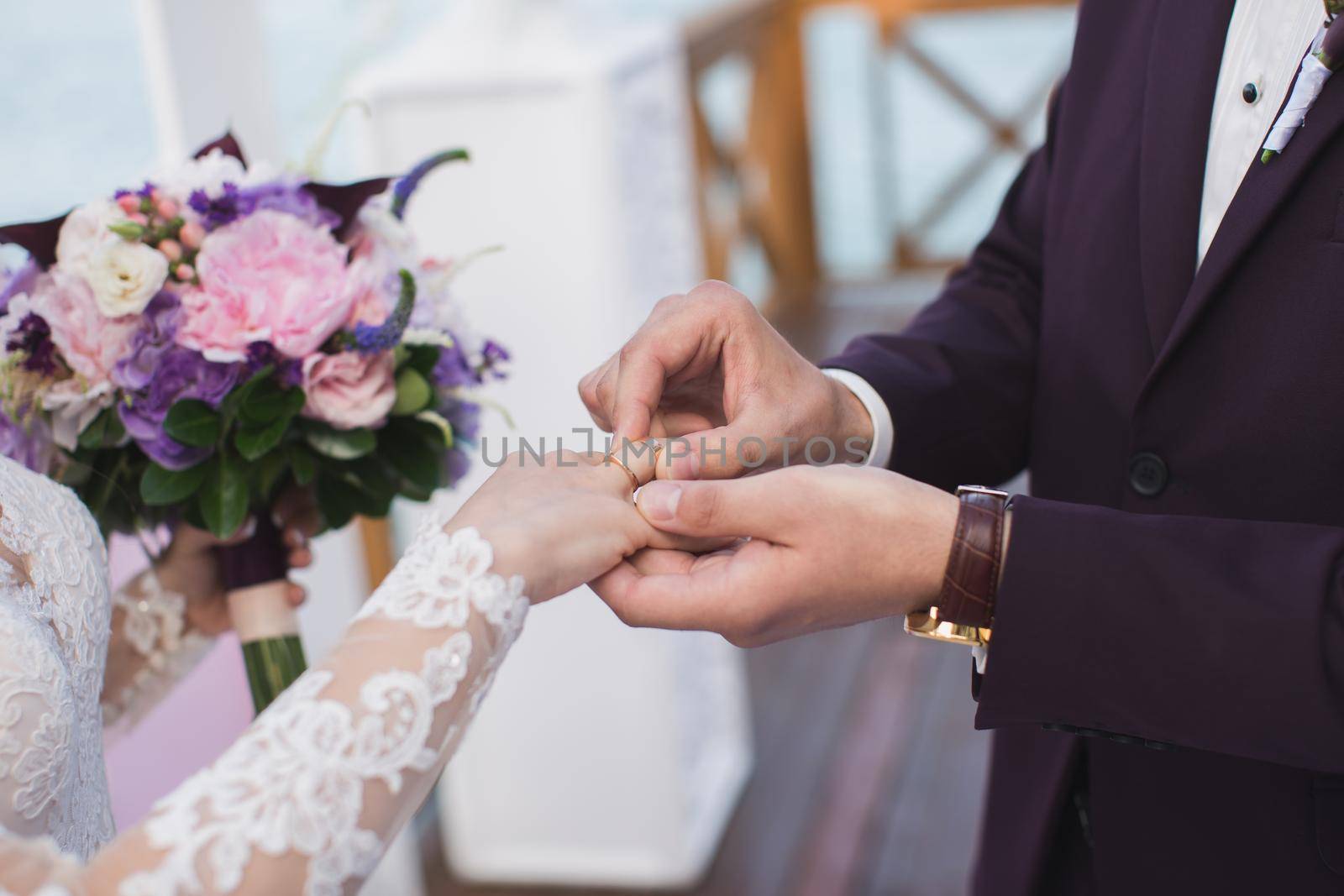 The groom puts a ring on the bride's finger.