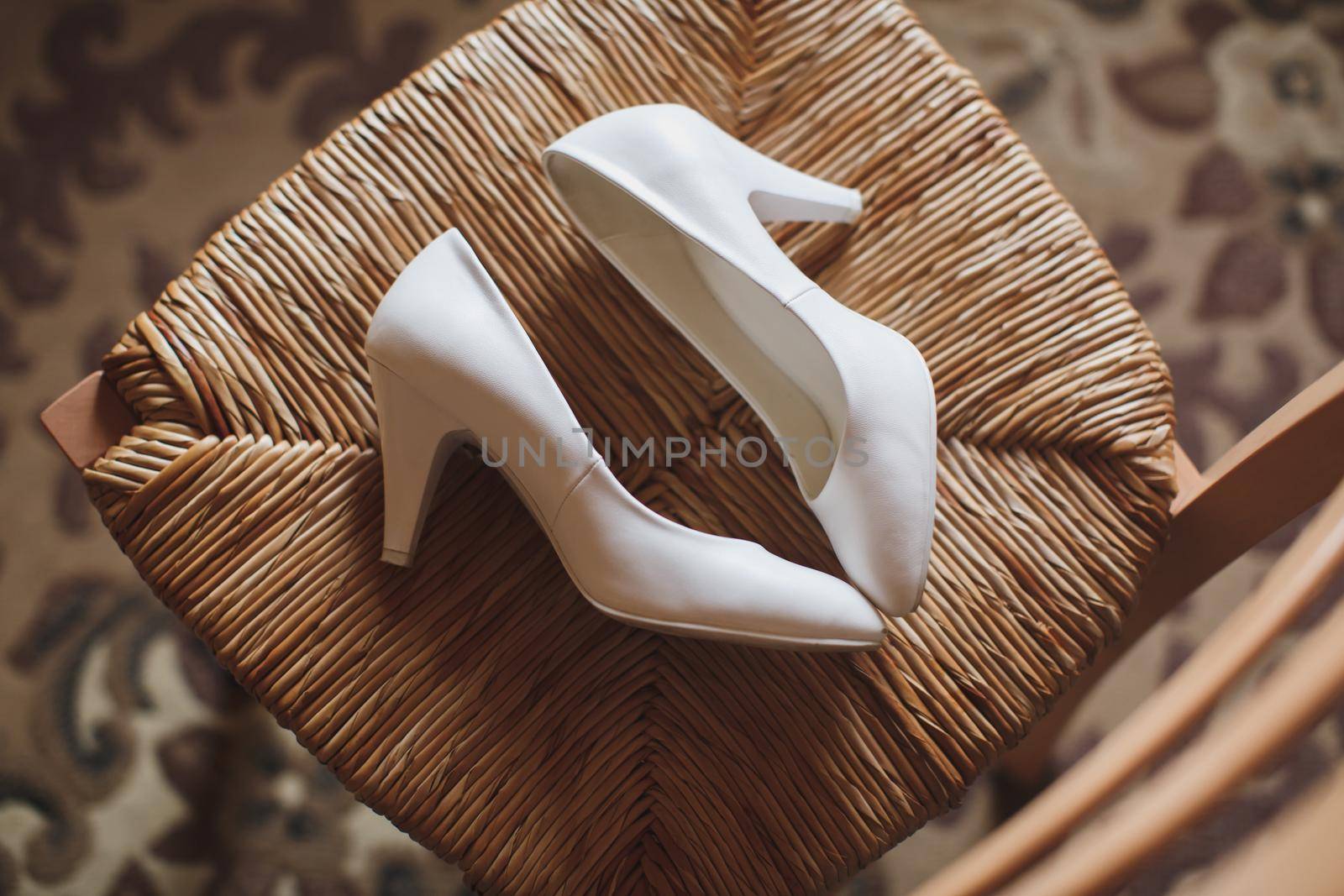 Women's shoes on a white chair on the wedding day by StudioPeace