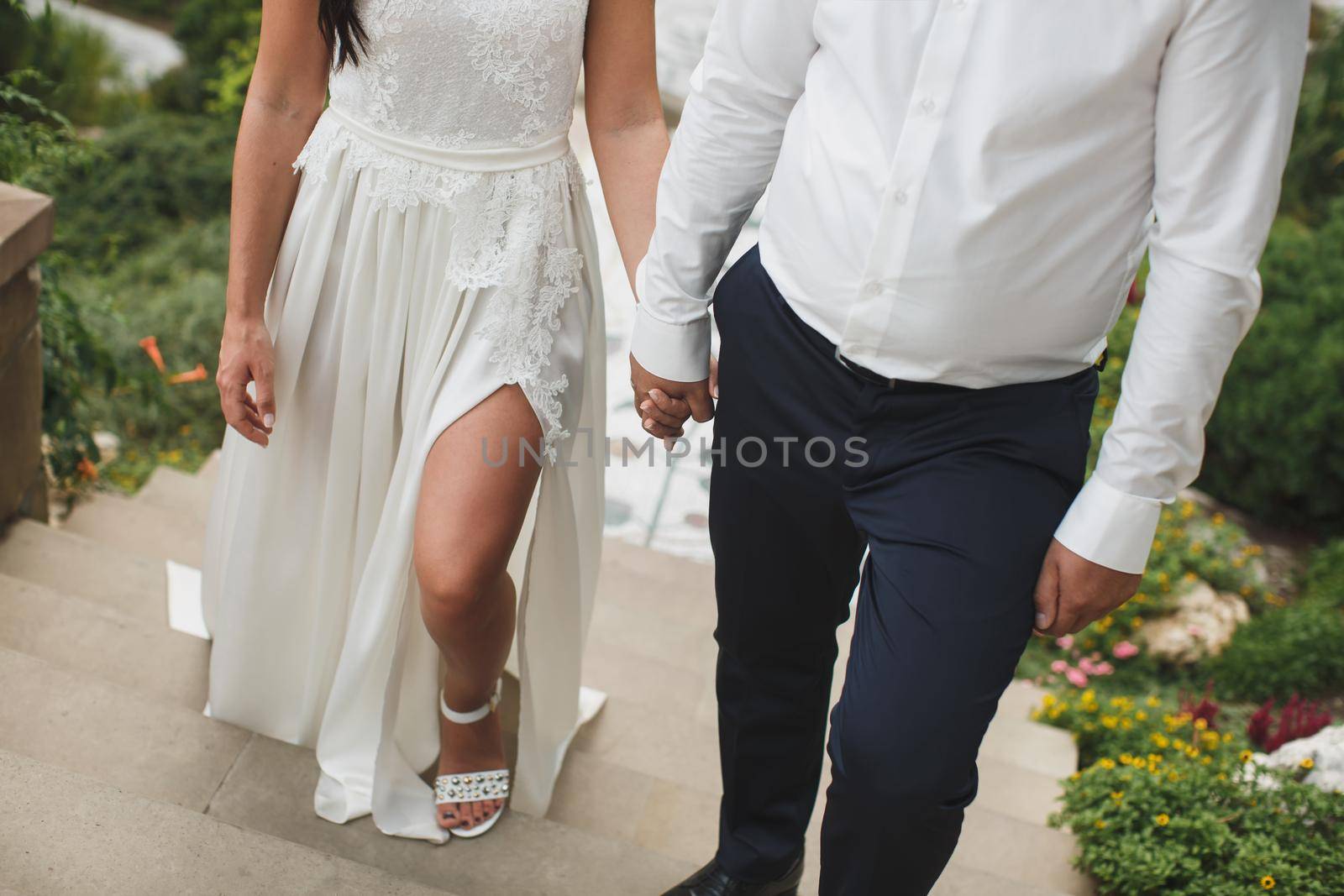 Bride and groom walking together holding their hands by StudioPeace