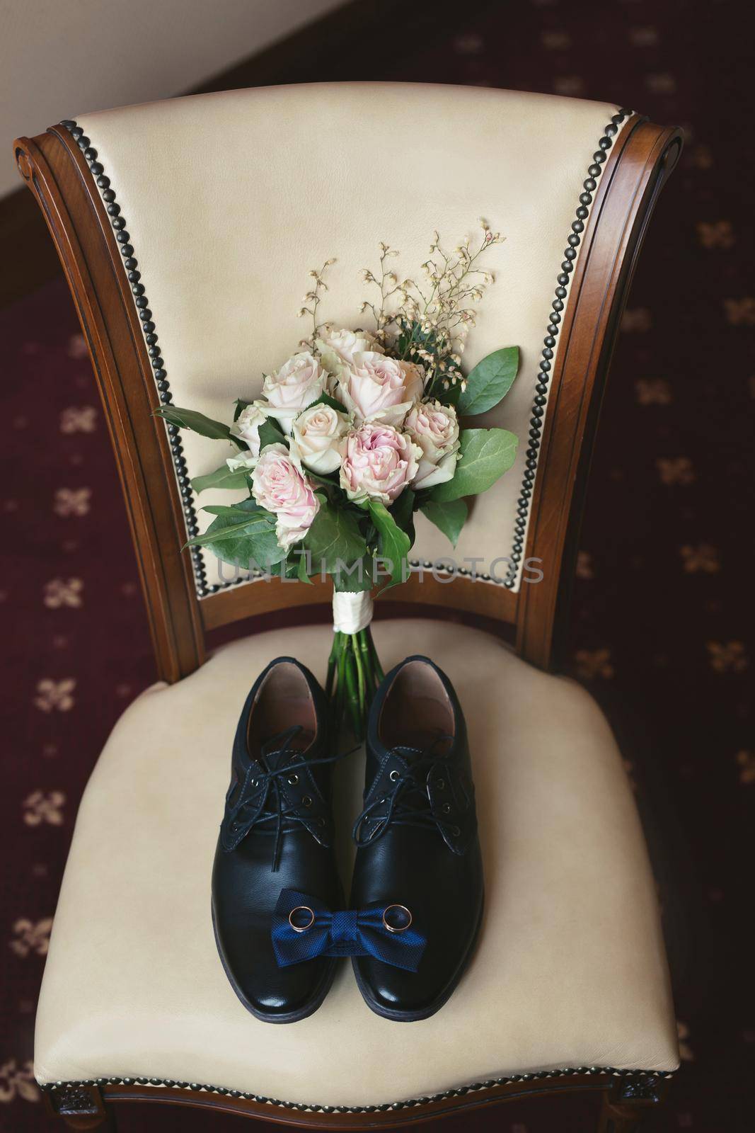Men's shoes , bouquet, tie and rings on a chair. The view from the top