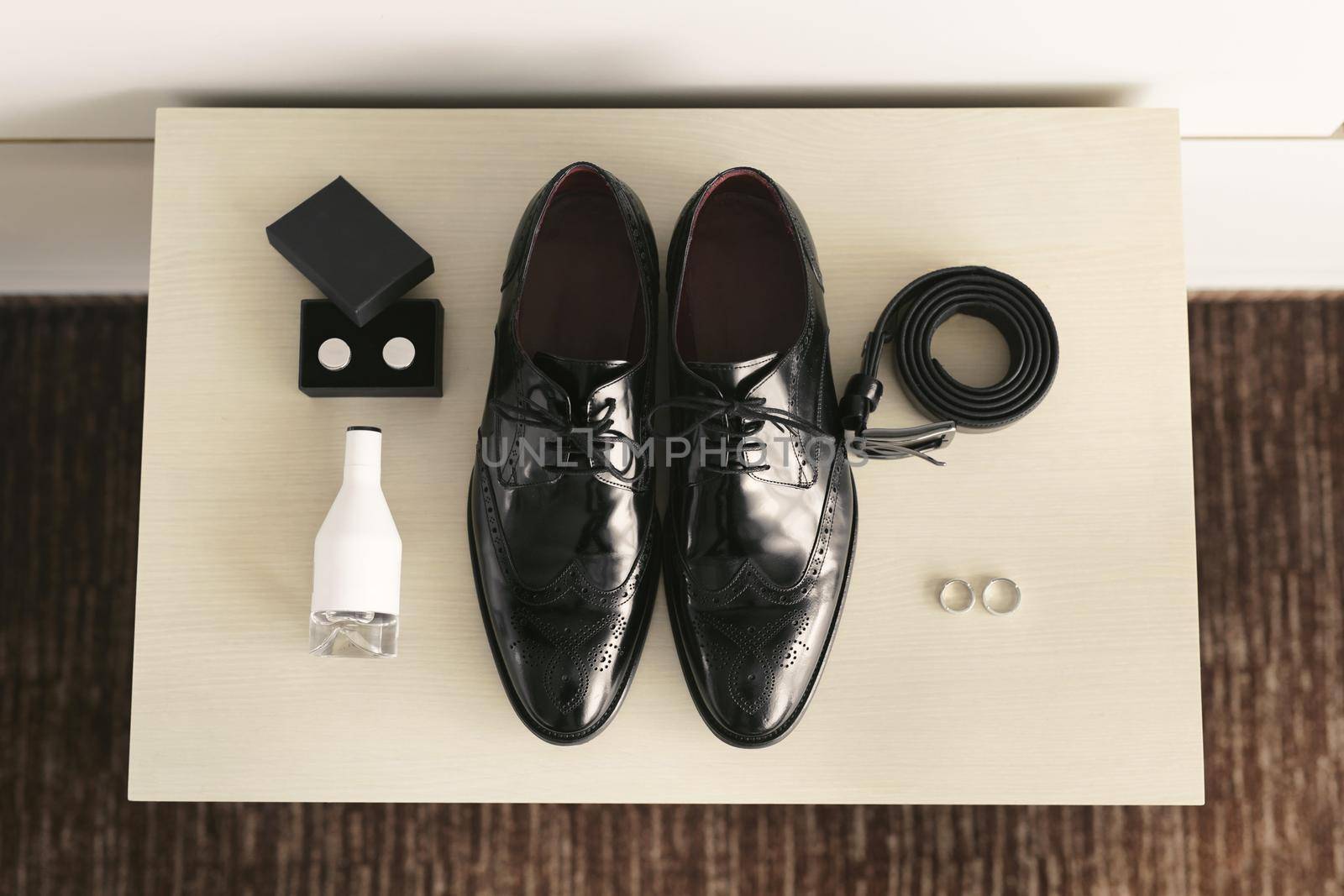Groom is gathering in the morning.Men's classic shoes, belt,toilette, perfume, leather strap watch, wedding rings.