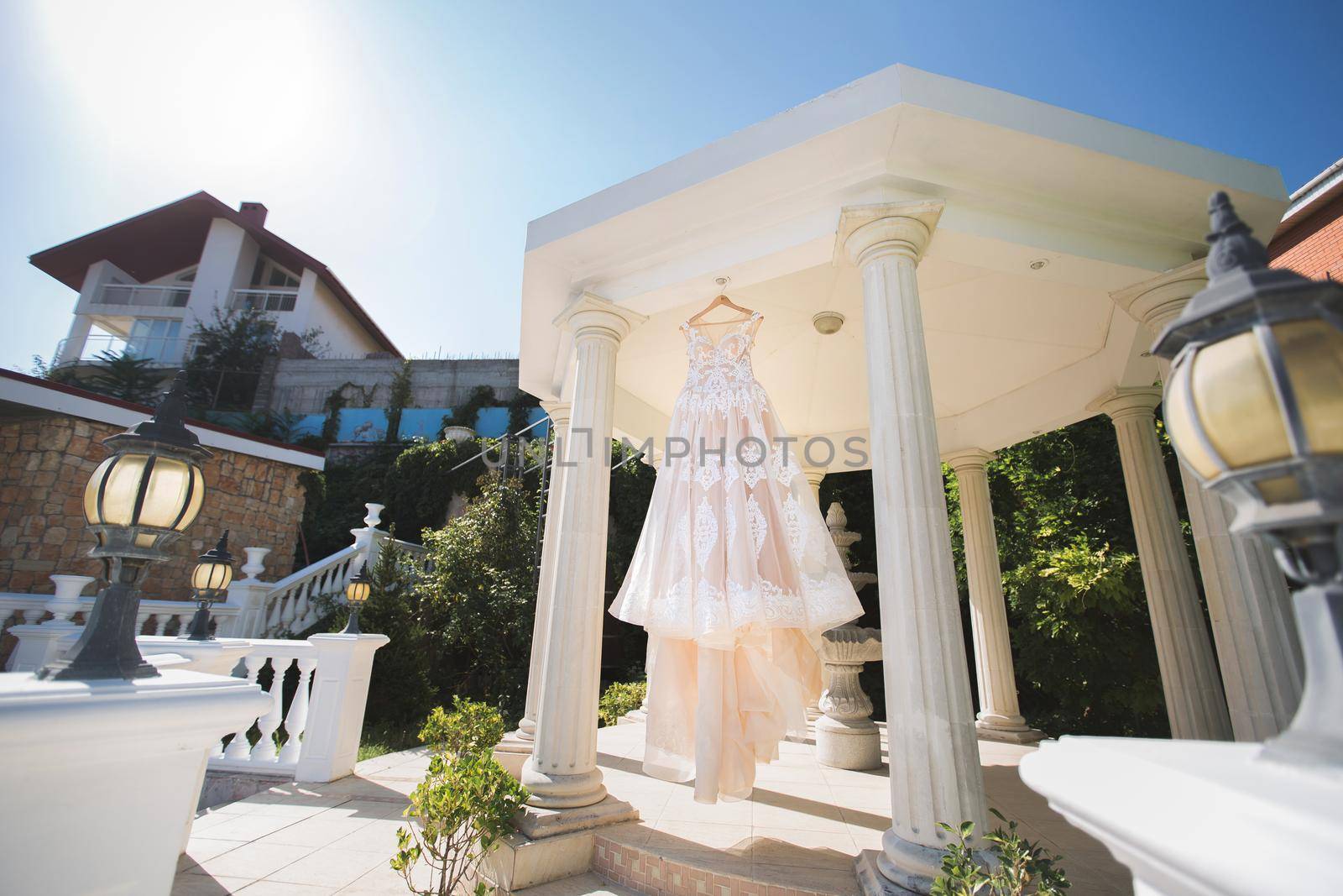 The wedding dress is hanging in a beautiful white gazebo.