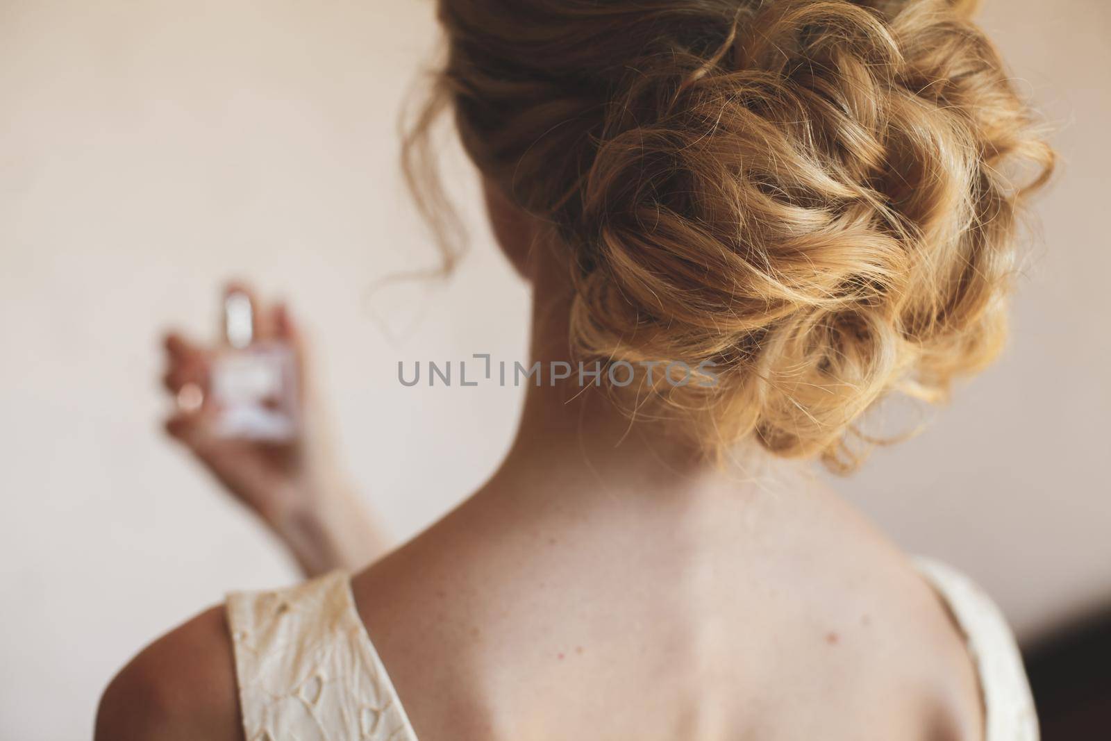The blonde bride enjoys perfume during the wedding preparations.