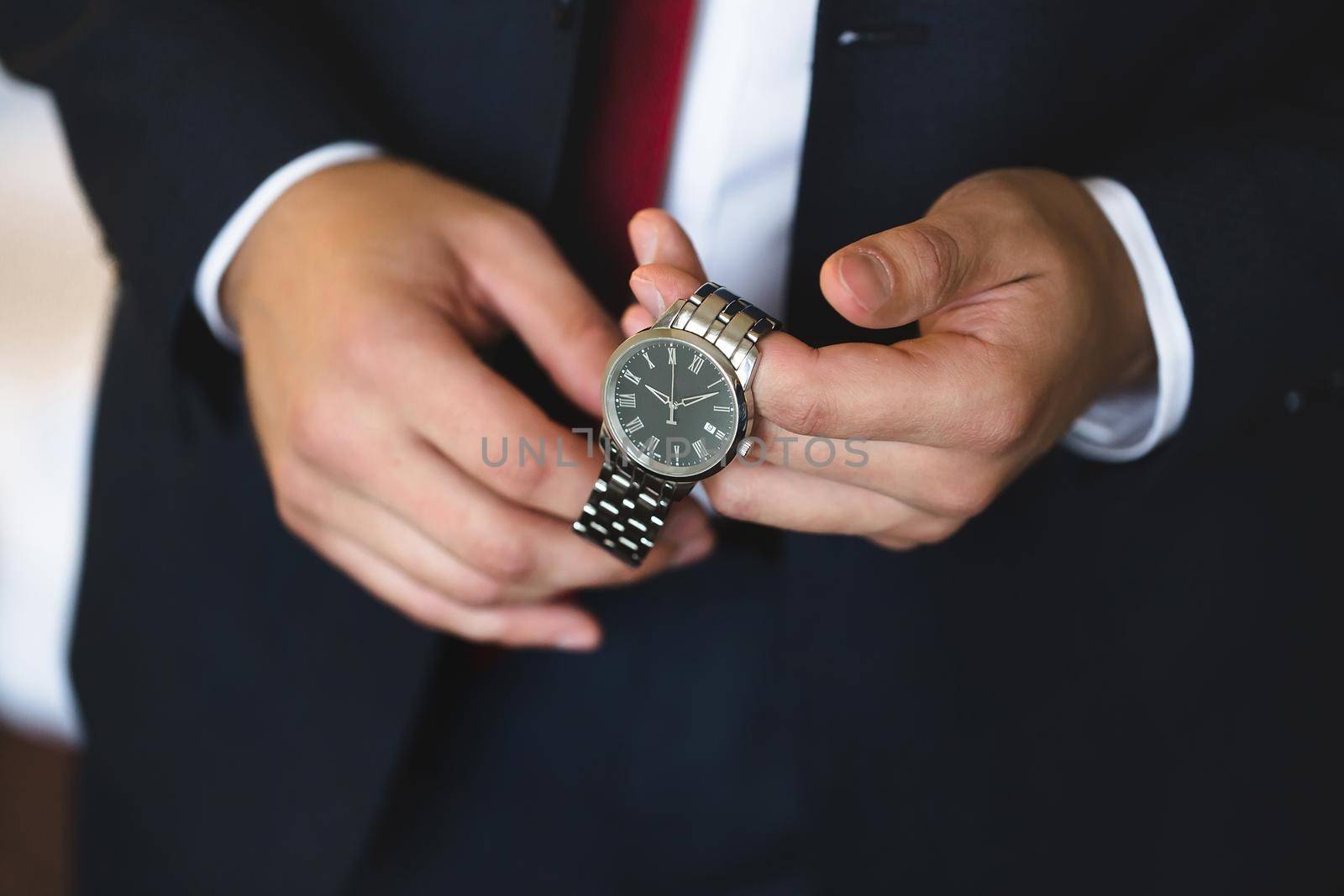 Close-up hands of the groom with a clock