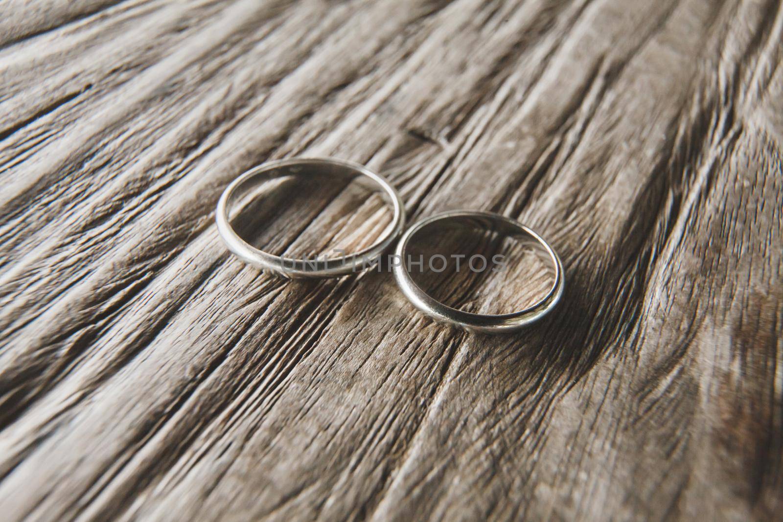 Macro shooting of gold wedding rings on the texture of wood.