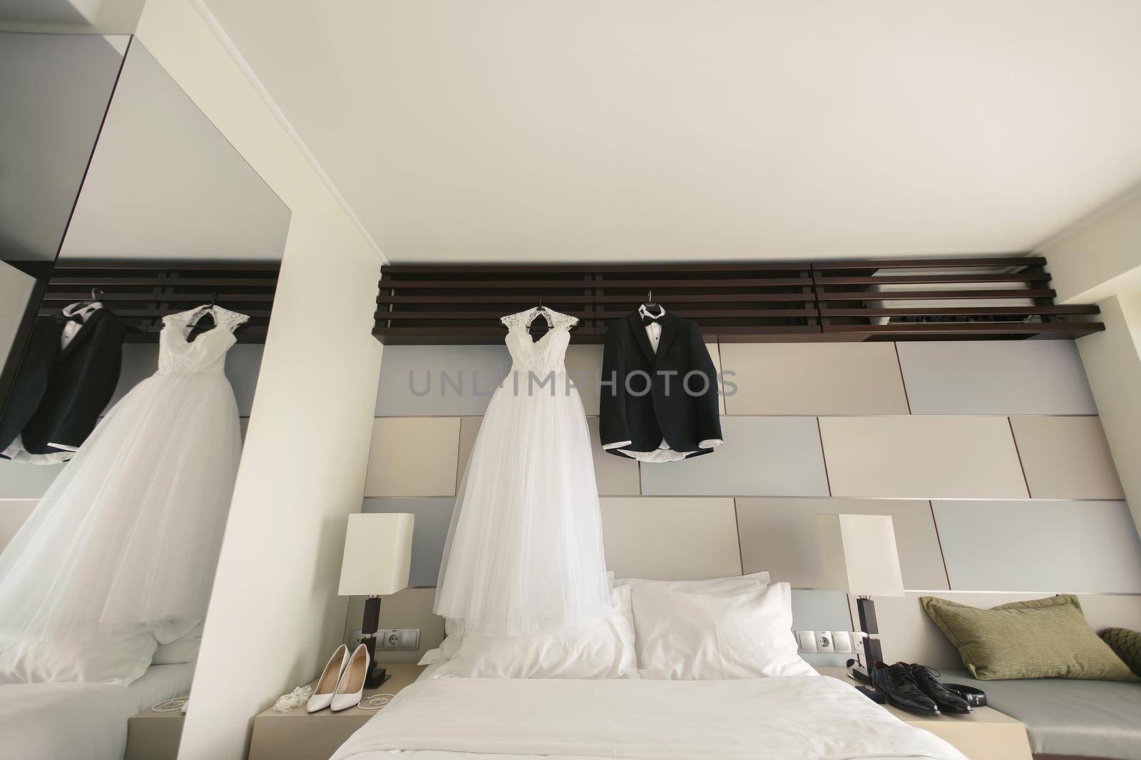 Dress of the bride and groom's suit hang on a hanger. by StudioPeace