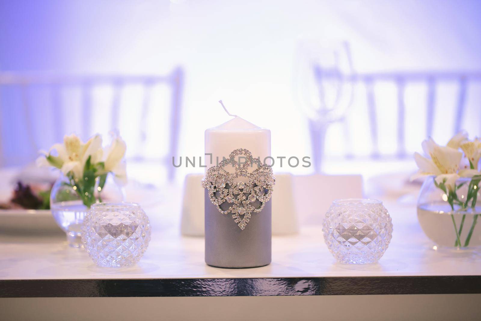 Wedding decor in silver style with crystals, lace and flowers. Wedding candles for the family hearth
