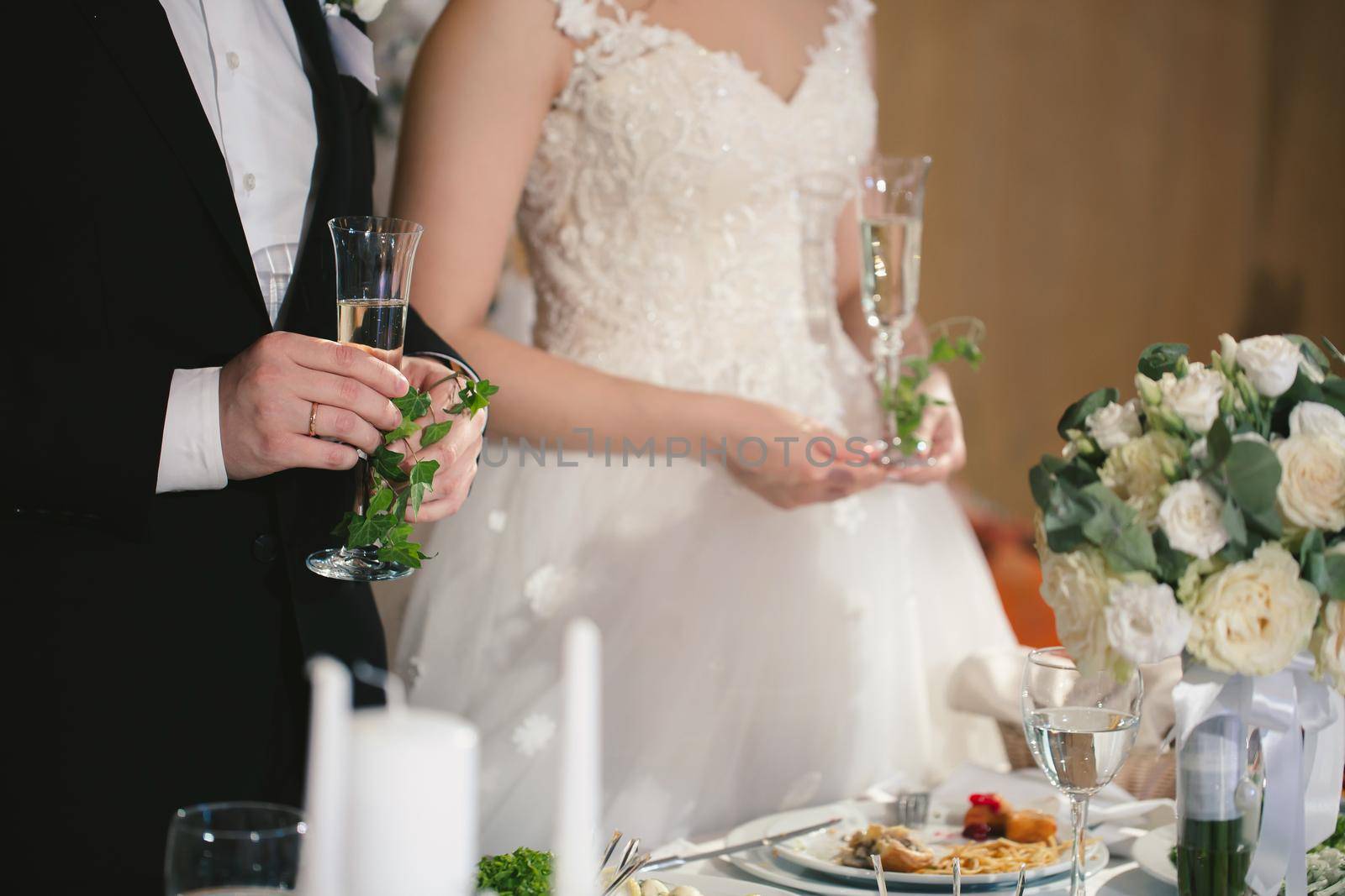 The bride and groom hold crystal glasses filled with champagne