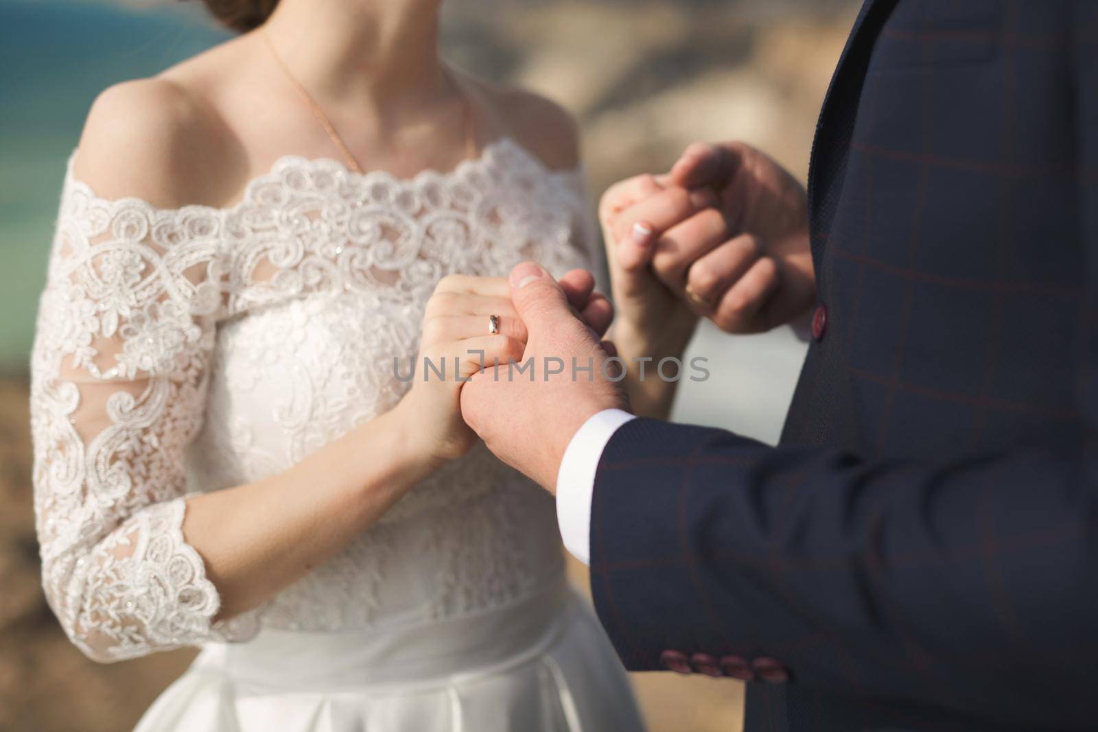Bride and groom hold hands during the wedding ceremony. by StudioPeace