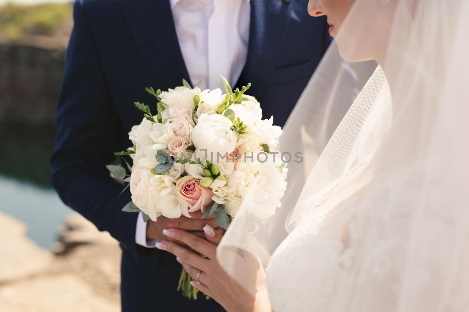 Delicate wedding bouquet of white, pink and powdery flowers in the hands of the bride.