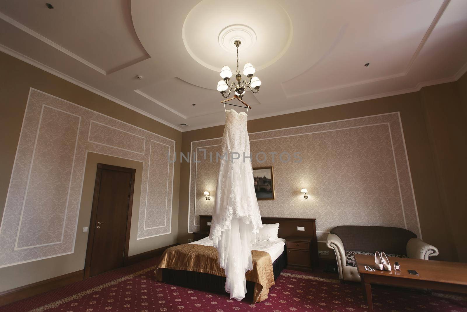 Luxurious white wedding dress hangs on hangers by StudioPeace