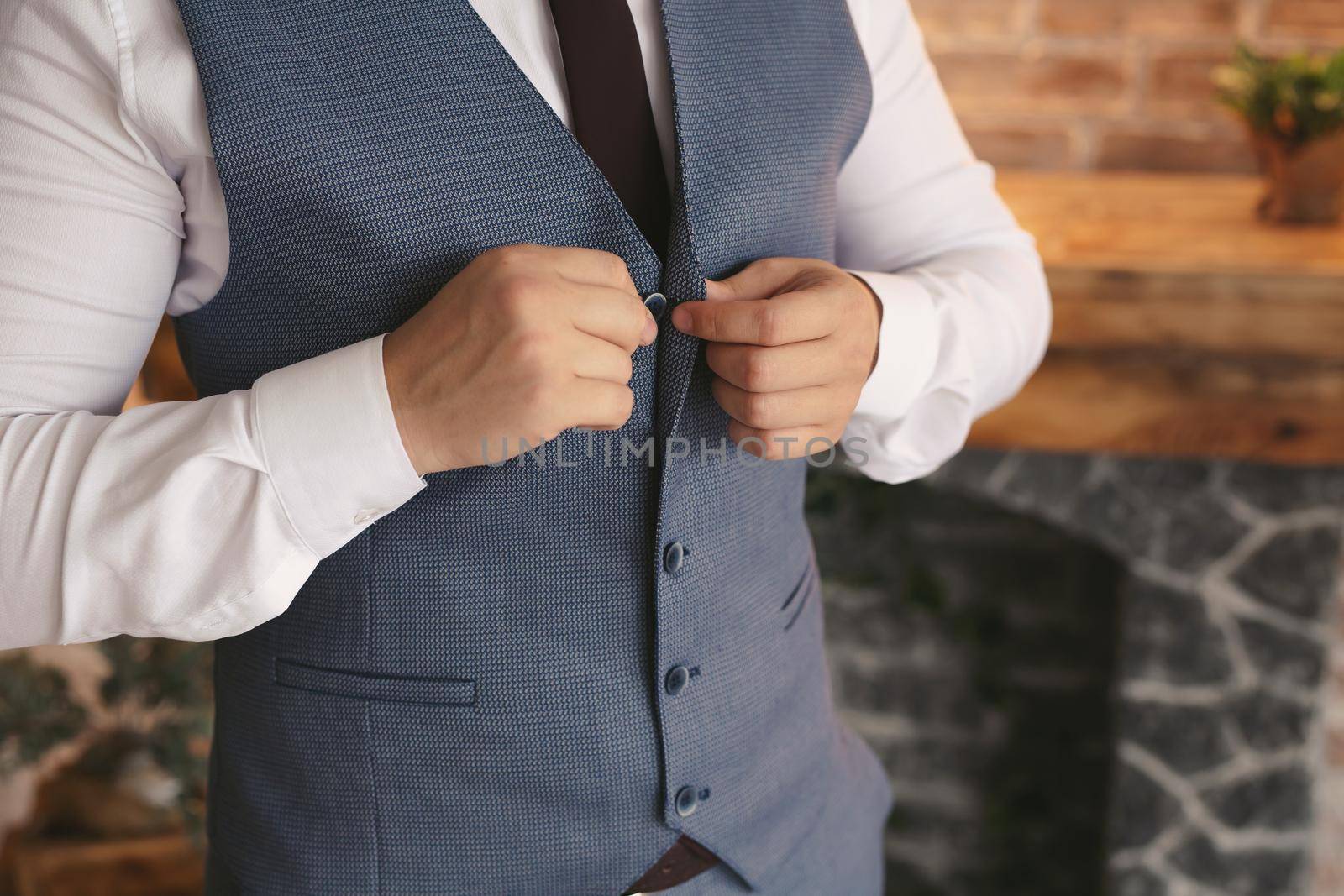 A man puts on a wedding suit and fastens a button by StudioPeace