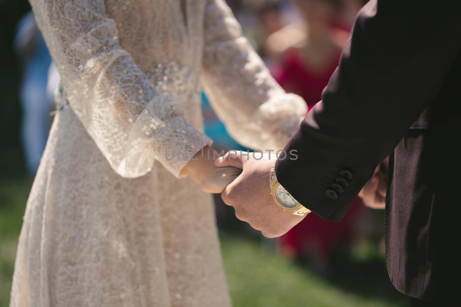 Bride and groom hold hands during the wedding ceremony. by StudioPeace