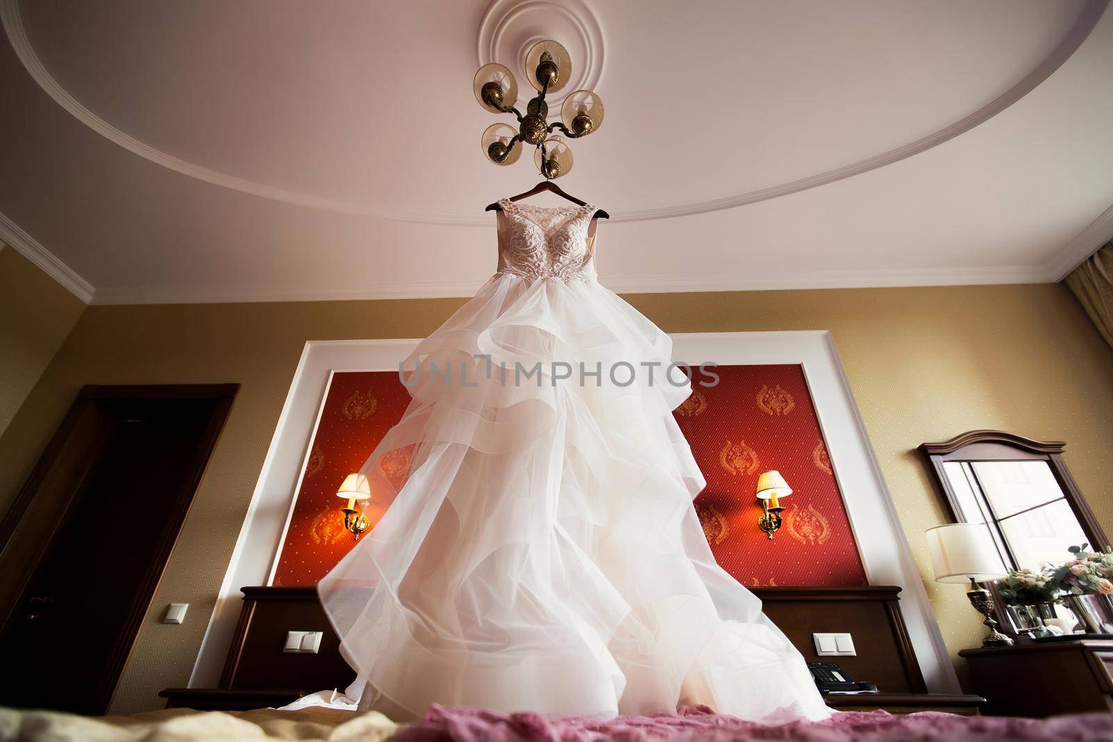 Luxurious white wedding dress hangs on hangers by StudioPeace