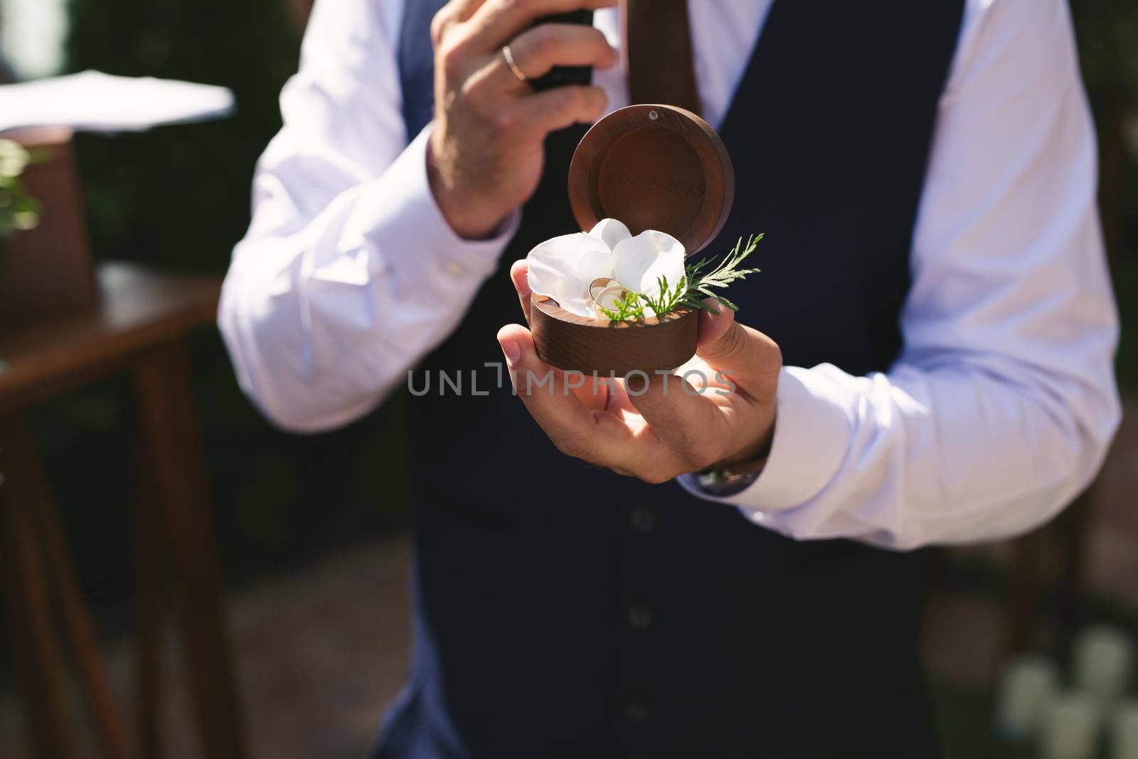 Wedding gold rings in a wooden box, wedding rings in the hands of the groom.