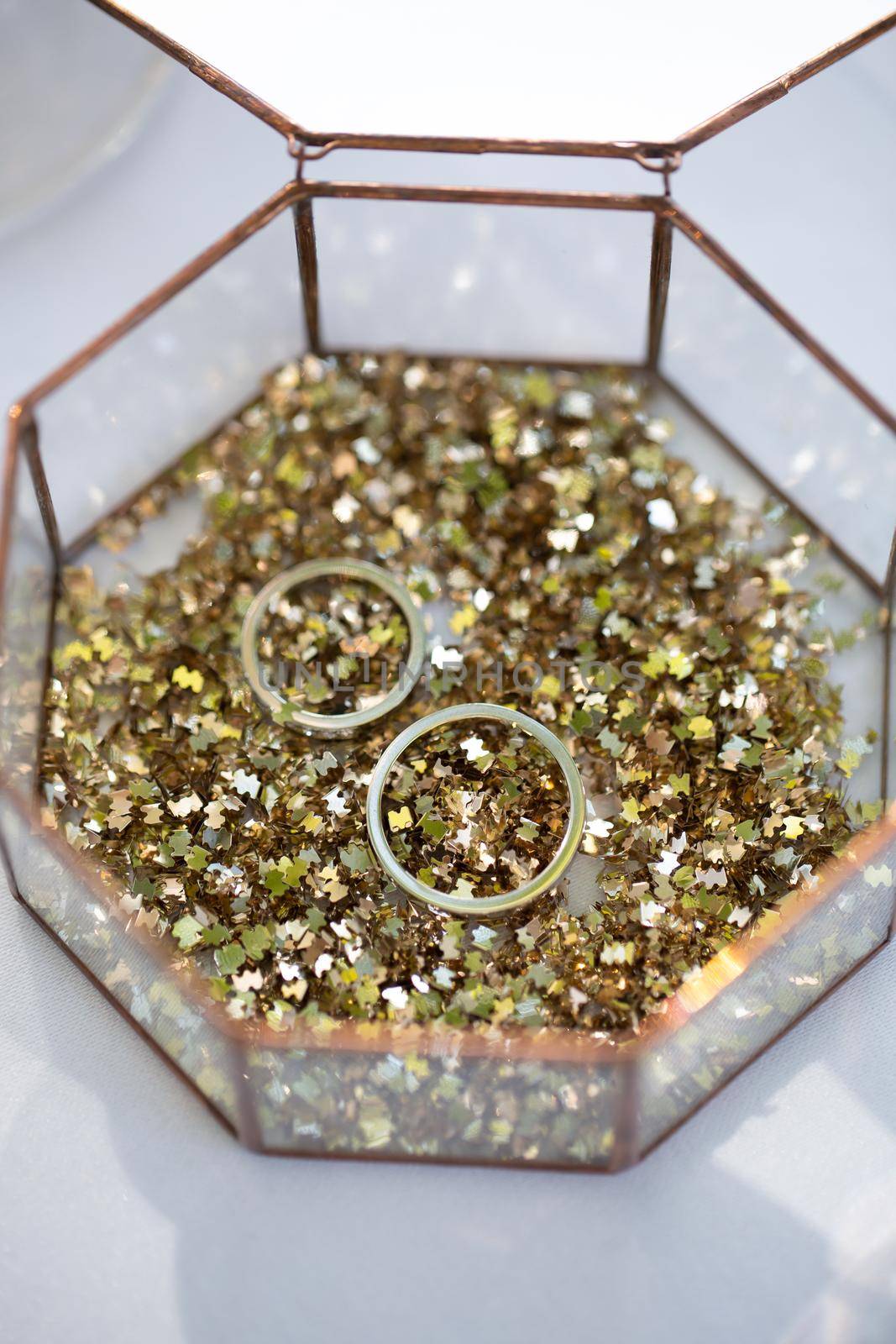 Glass box with wedding rings and gold sequins. by StudioPeace