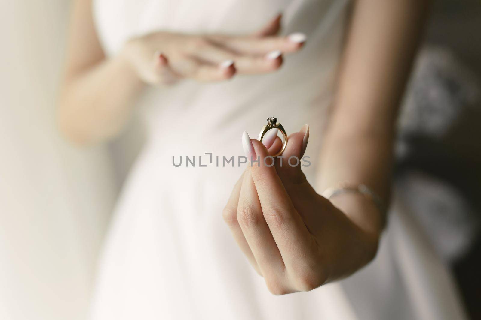 Close-up of the ring in the hands of the bride, who tries it on by StudioPeace