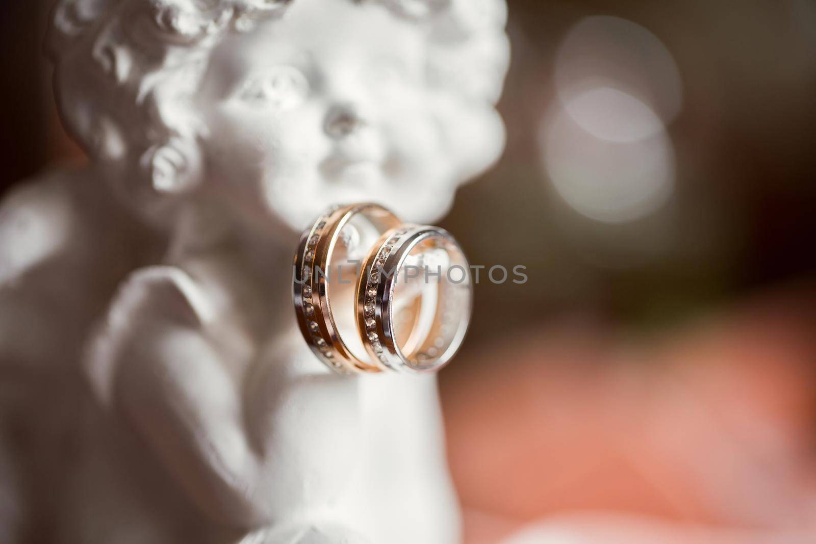 Statuette of an angel with wedding golden rings. by StudioPeace