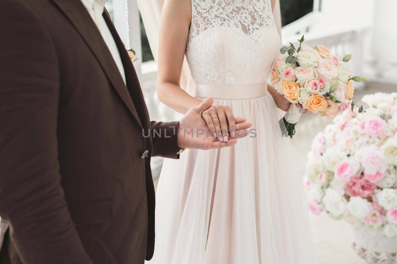 Bride and groom hold hands during the wedding ceremony. by StudioPeace