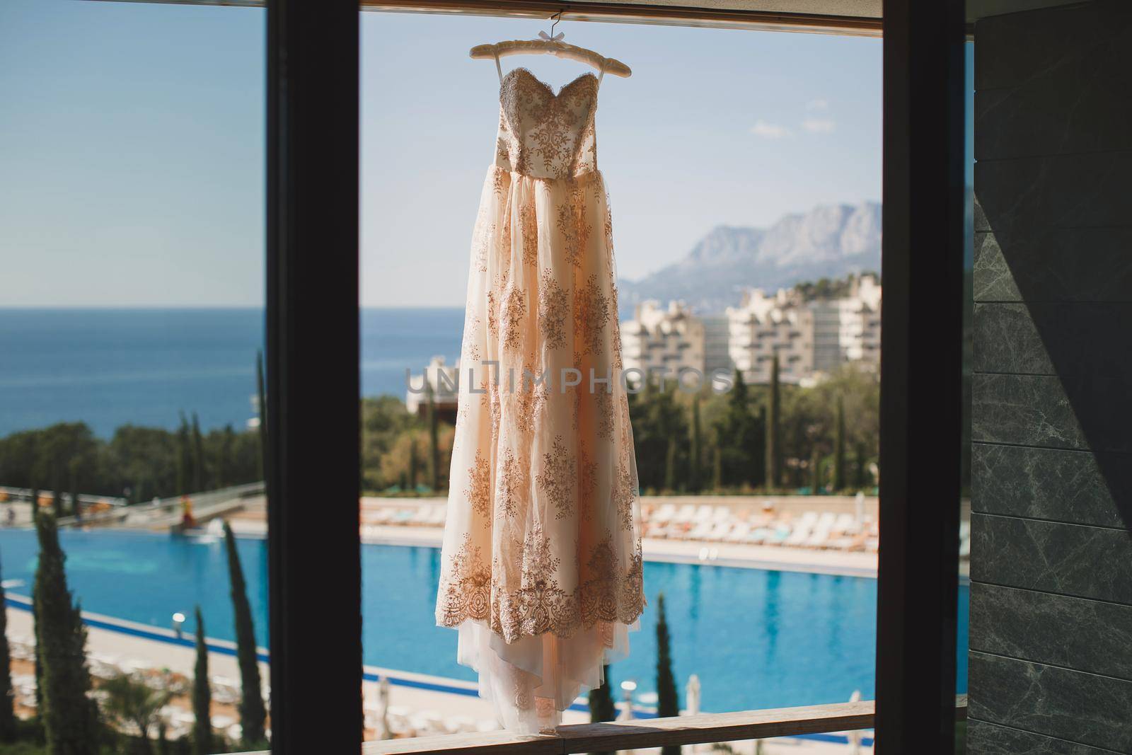 Wedding dress at the hotel on the background of the pool, ocean and mountains.