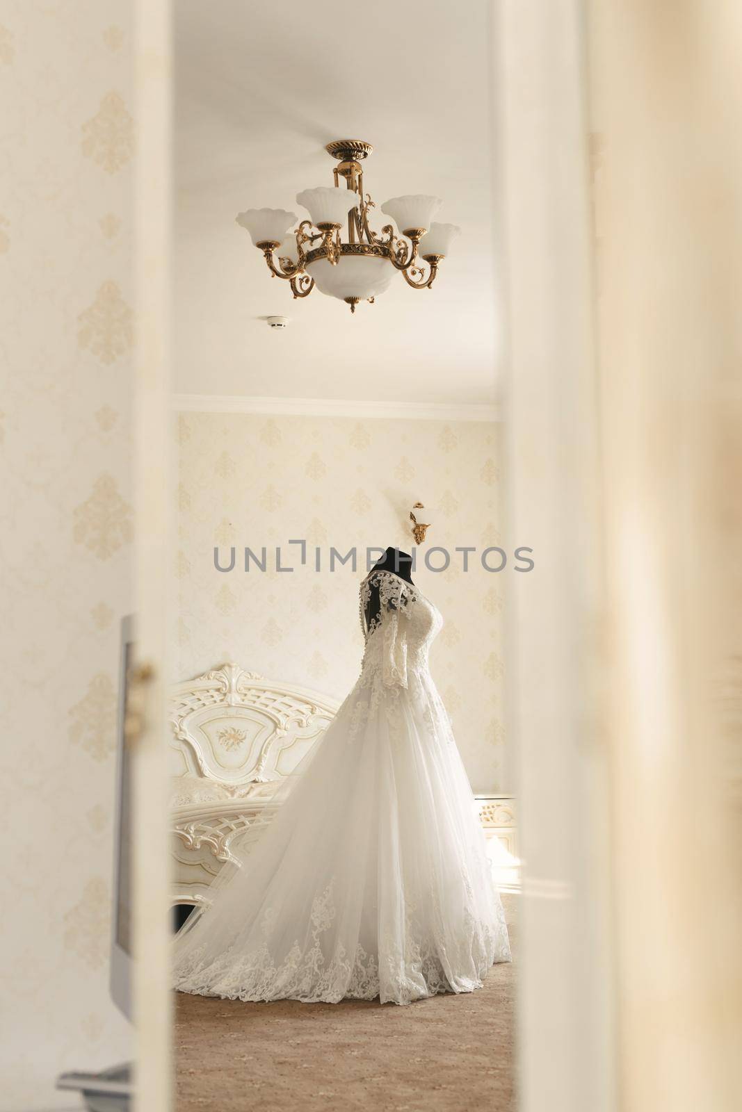 Chic wedding dress and veil on a mannequin in the bride 's gathering room. View through the doorway.