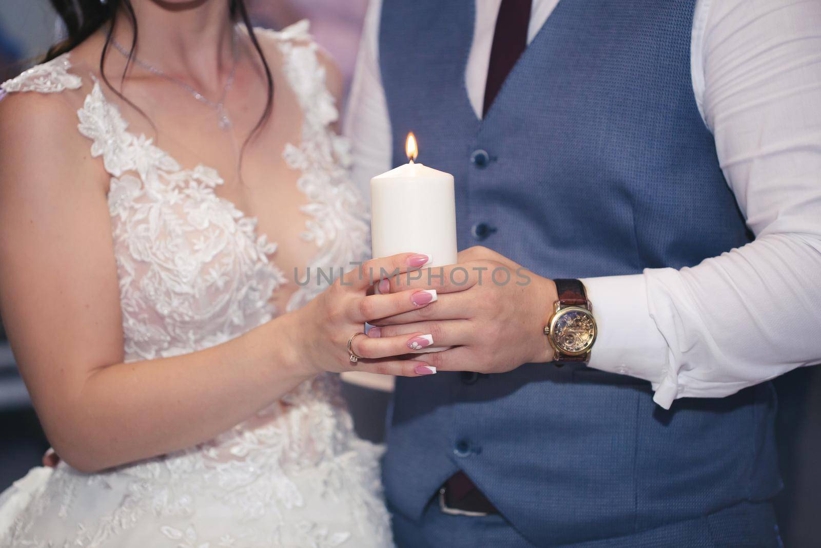 Wedding ceremony, paraphernalia, the bride and groom hold a large candle in their hand. by StudioPeace