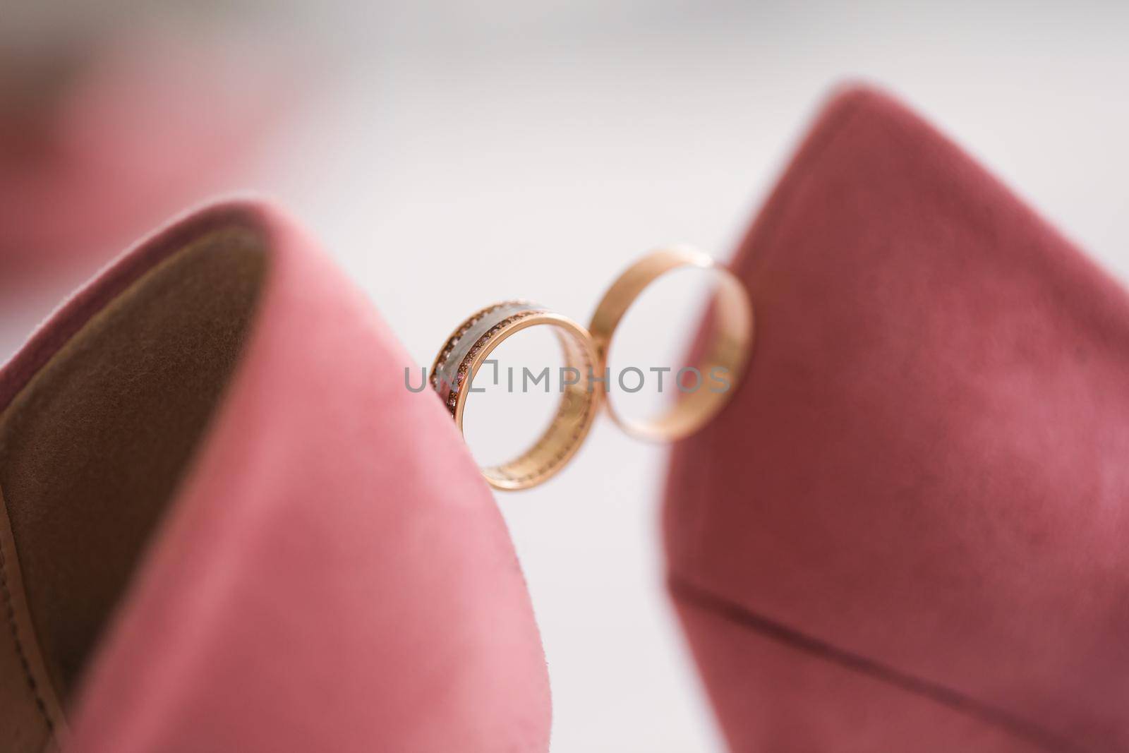 Gold wedding rings between the bride 's wedding shoes. by StudioPeace