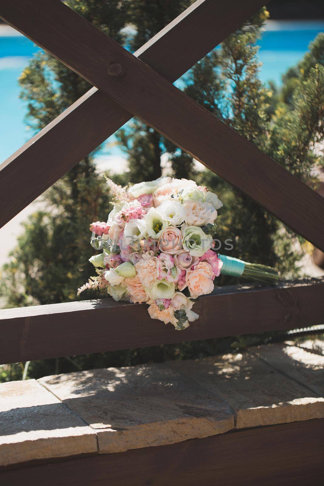 Wedding bouquet in a wooden gazebo on the background of the pool.