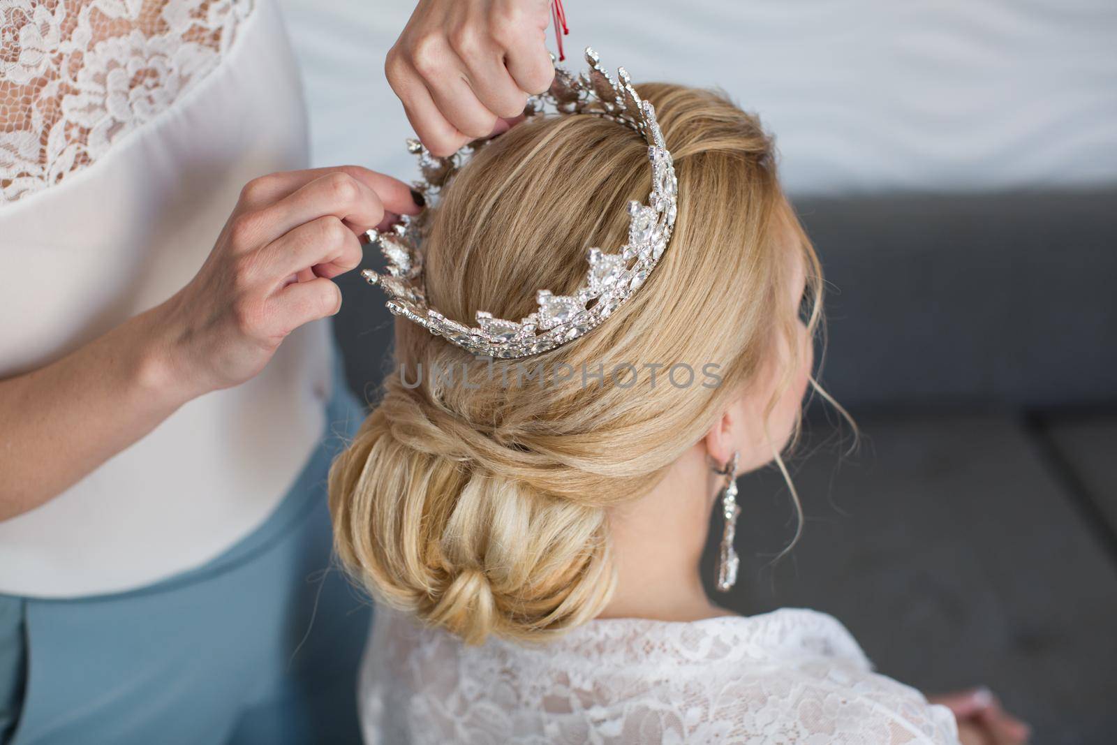 The stylist puts on the bride's crown by StudioPeace