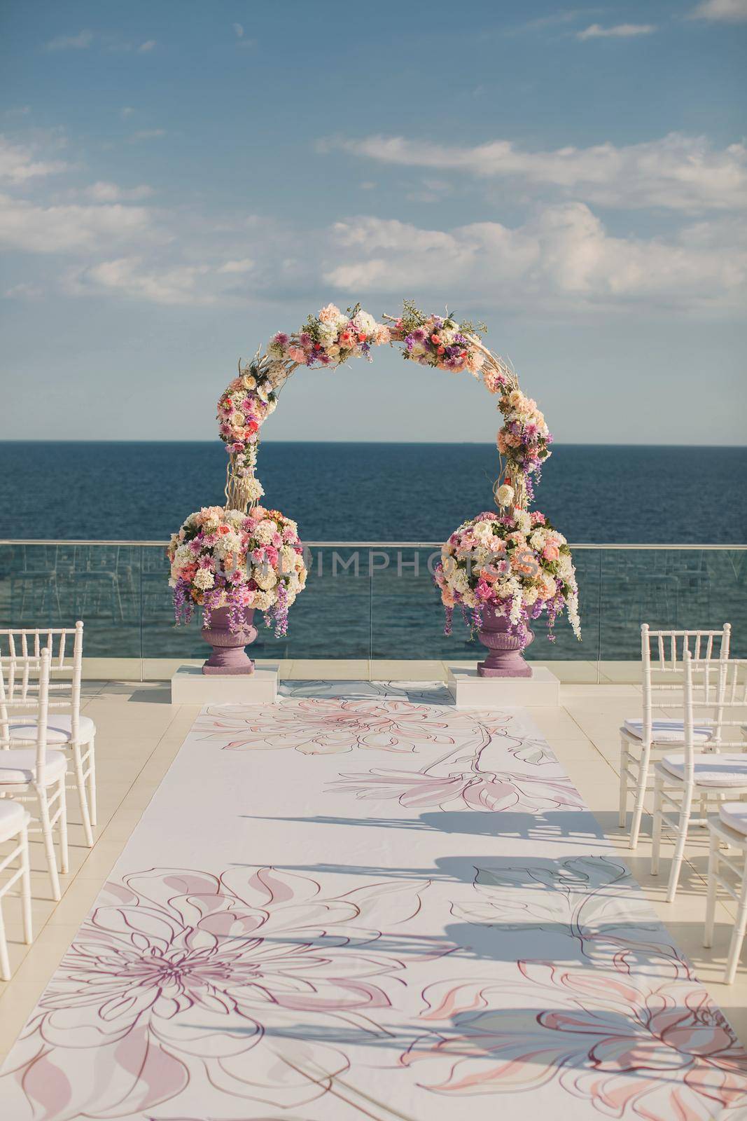 Wedding arch with fresh flowers on a sea background. Vases with fresh flowers.