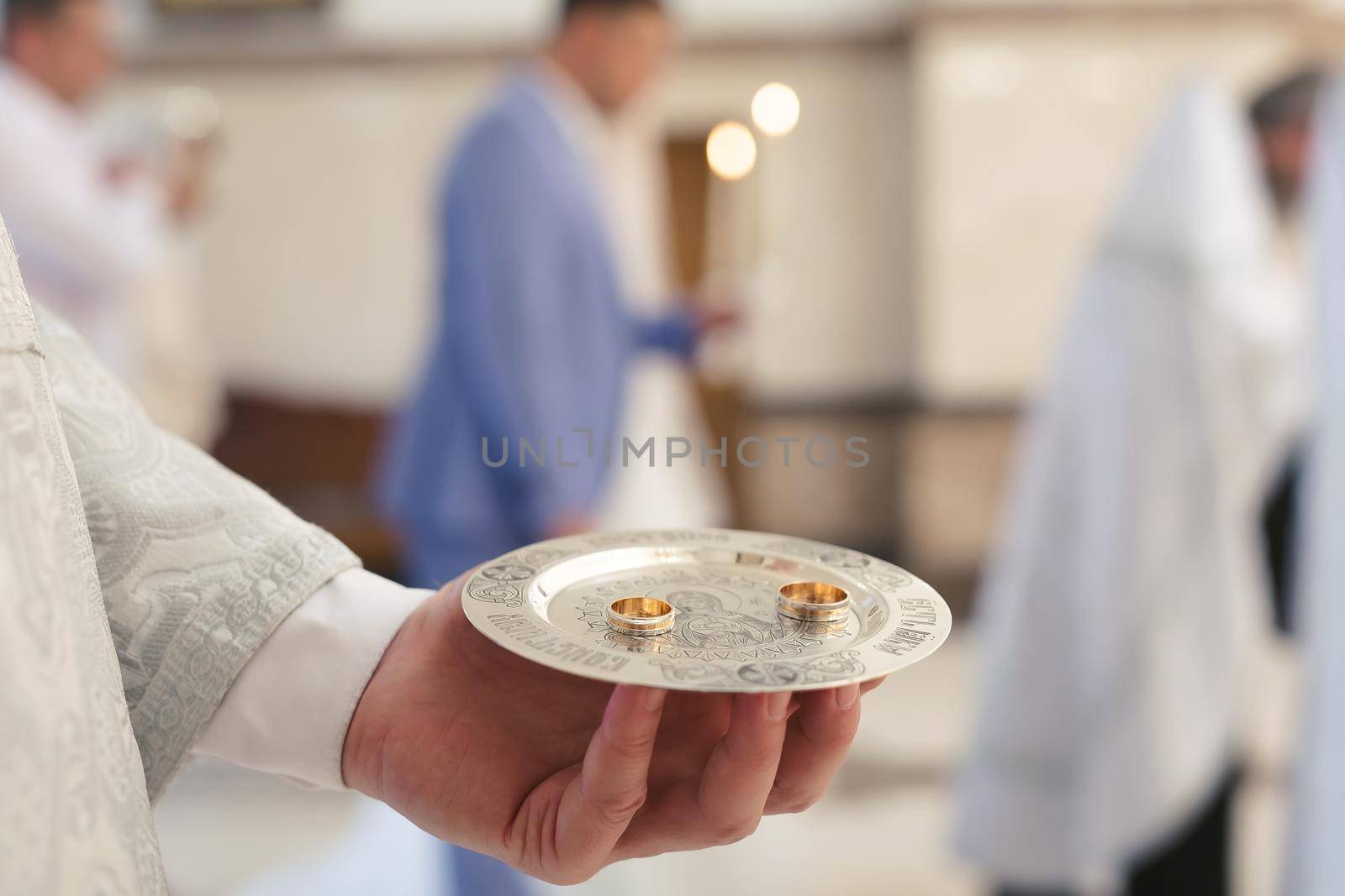 Close-up photo of a wedding ring held by a priest in a church before the wedding ceremony. by StudioPeace