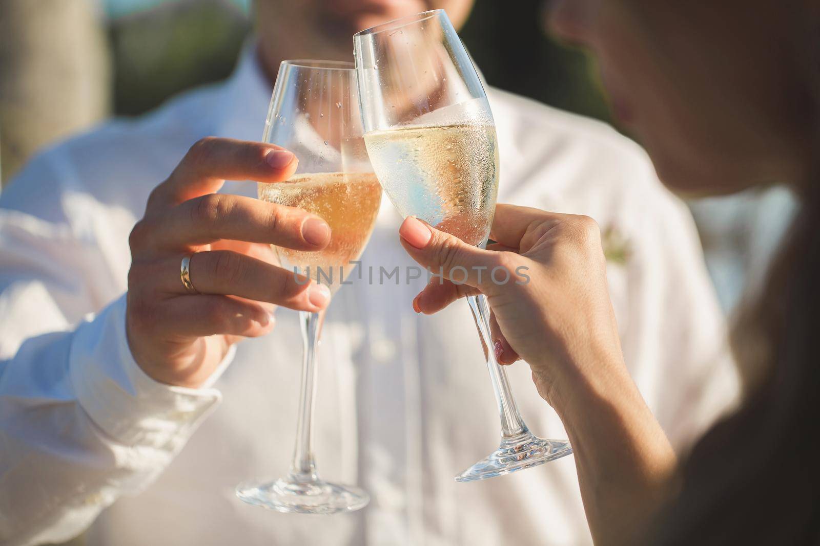 Bride and groom are holding champagne glasses. by StudioPeace