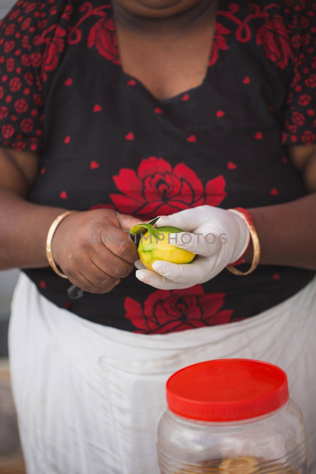 A woman peels mango at a wedding reception by StudioPeace