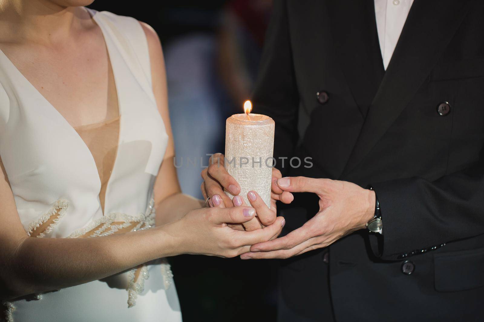 bride and groom hold a candle in their hands