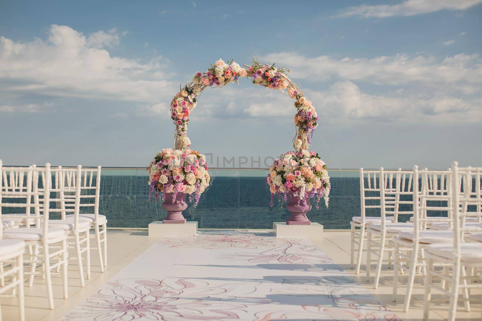 Wedding arch with fresh flowers on a sea background. Vases with fresh flowers.