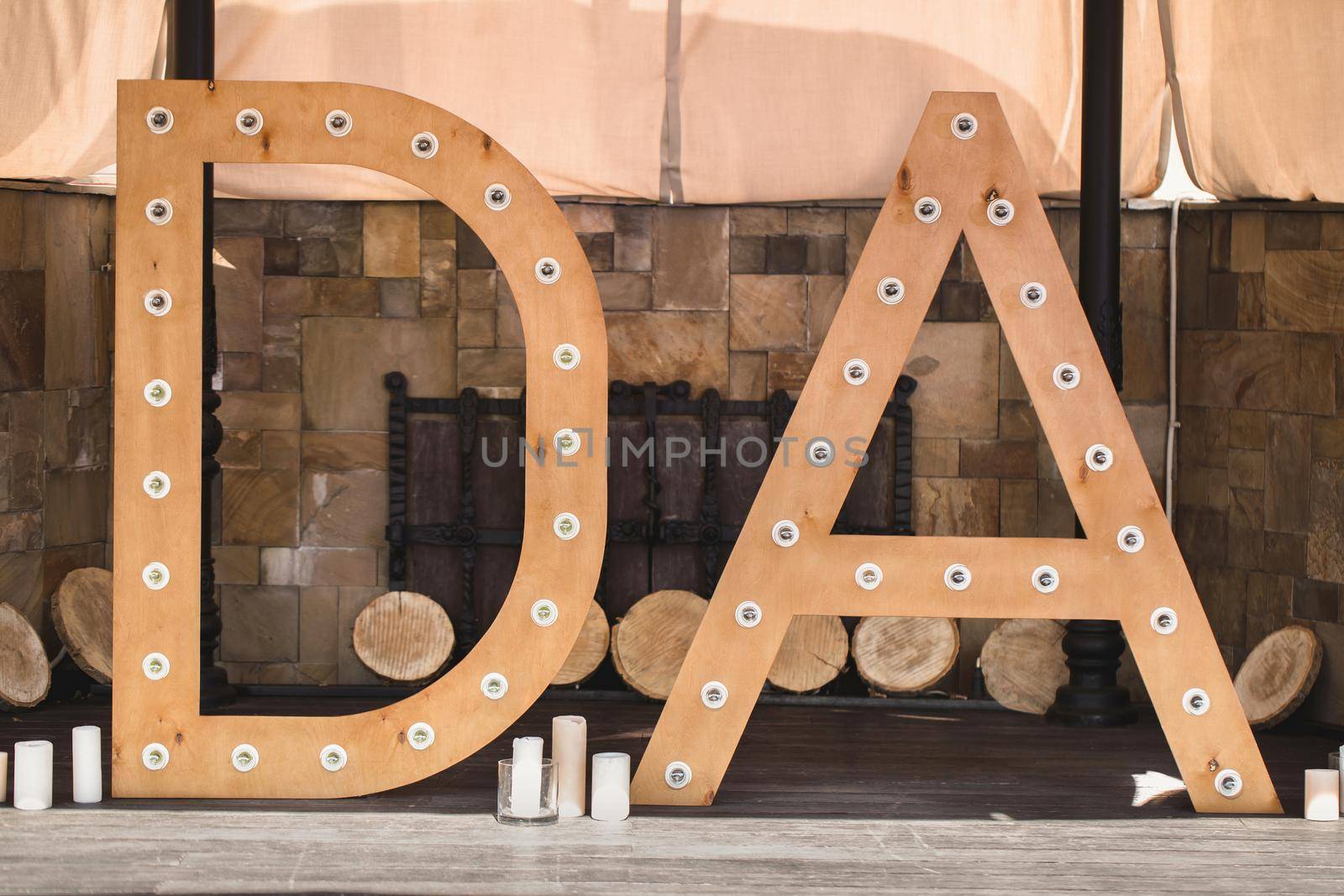 Wooden initials of the bride and groom with bright lights at the wedding.