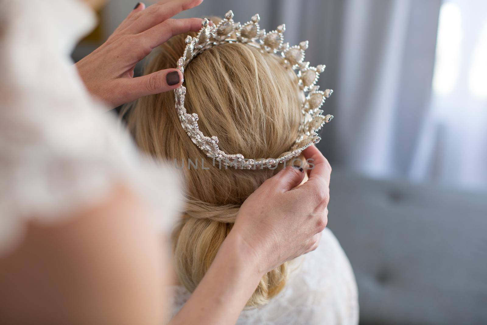 The stylist puts on the bride's crown.