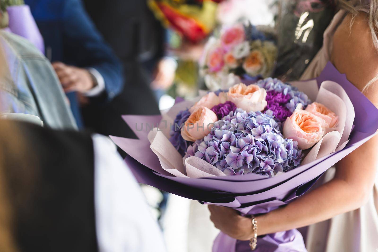 A very nice young woman is holding a large and beautiful bouquet. A wedding gift for the bride.