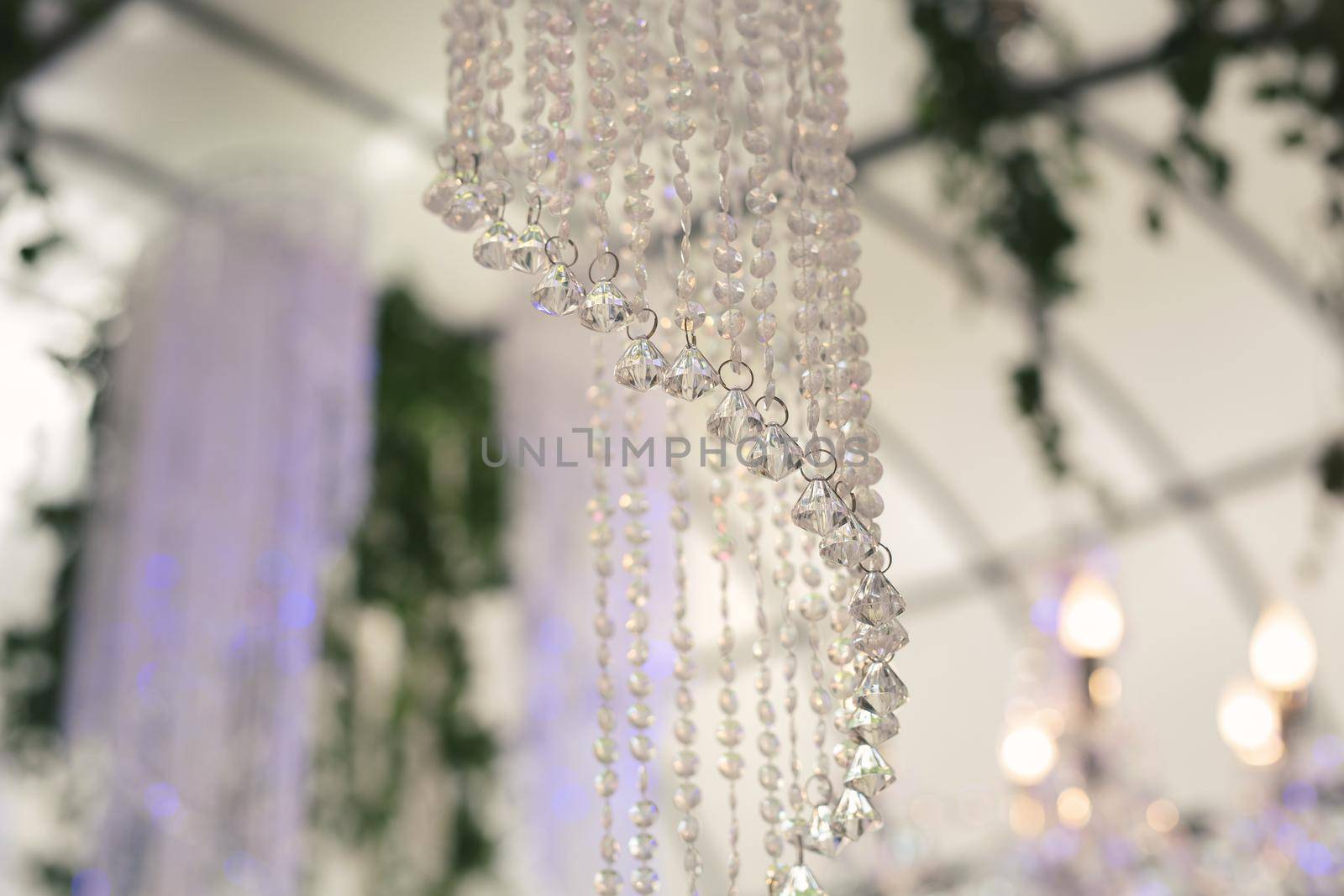 Beautiful luxurious romantic decor for a wedding celebration. The arch is decorated with draped fabric and a crystal chandelier by StudioPeace