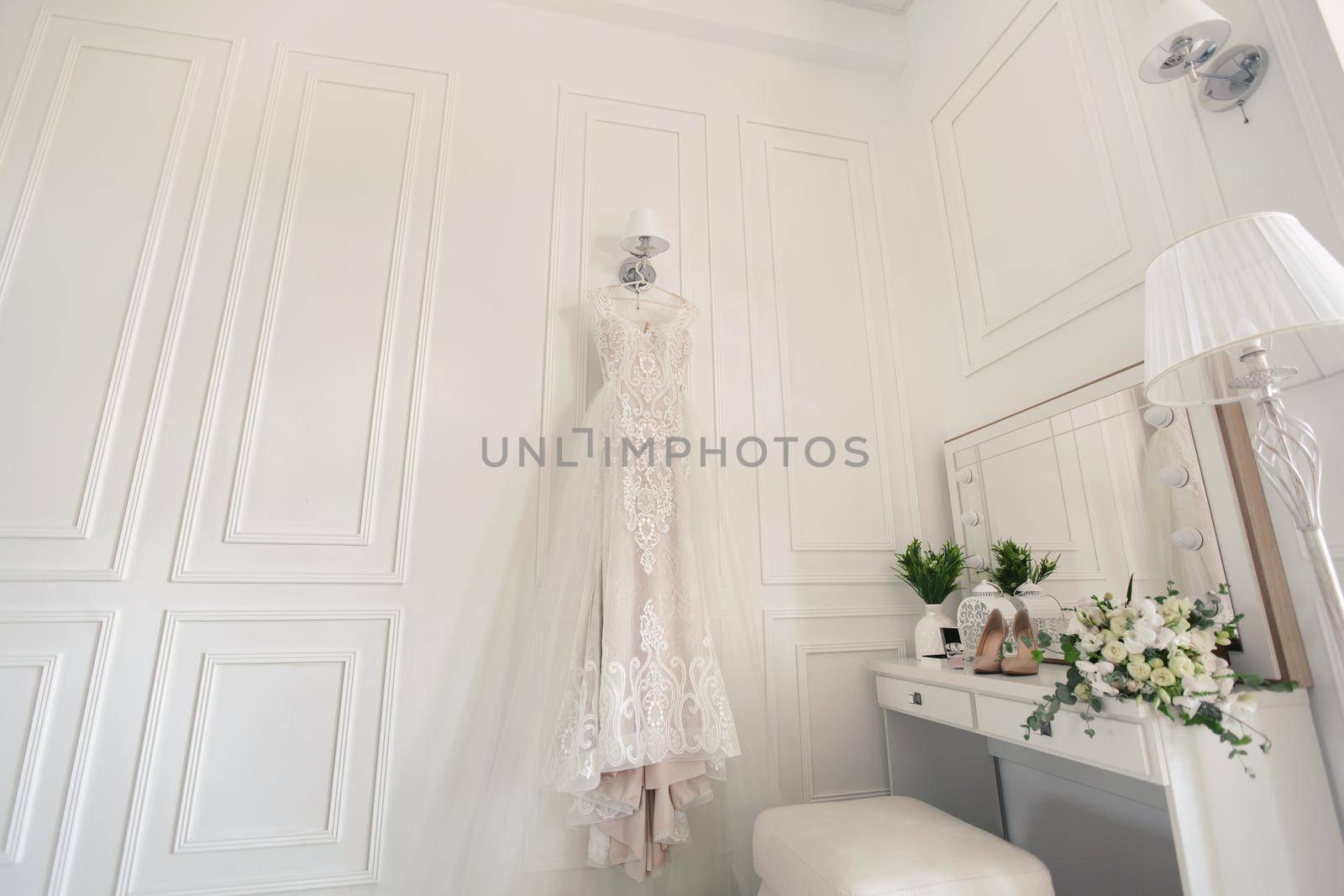 Elegant wedding white dress hanging on a wall during a wedding preparation. Bride's morning. Before ceremony