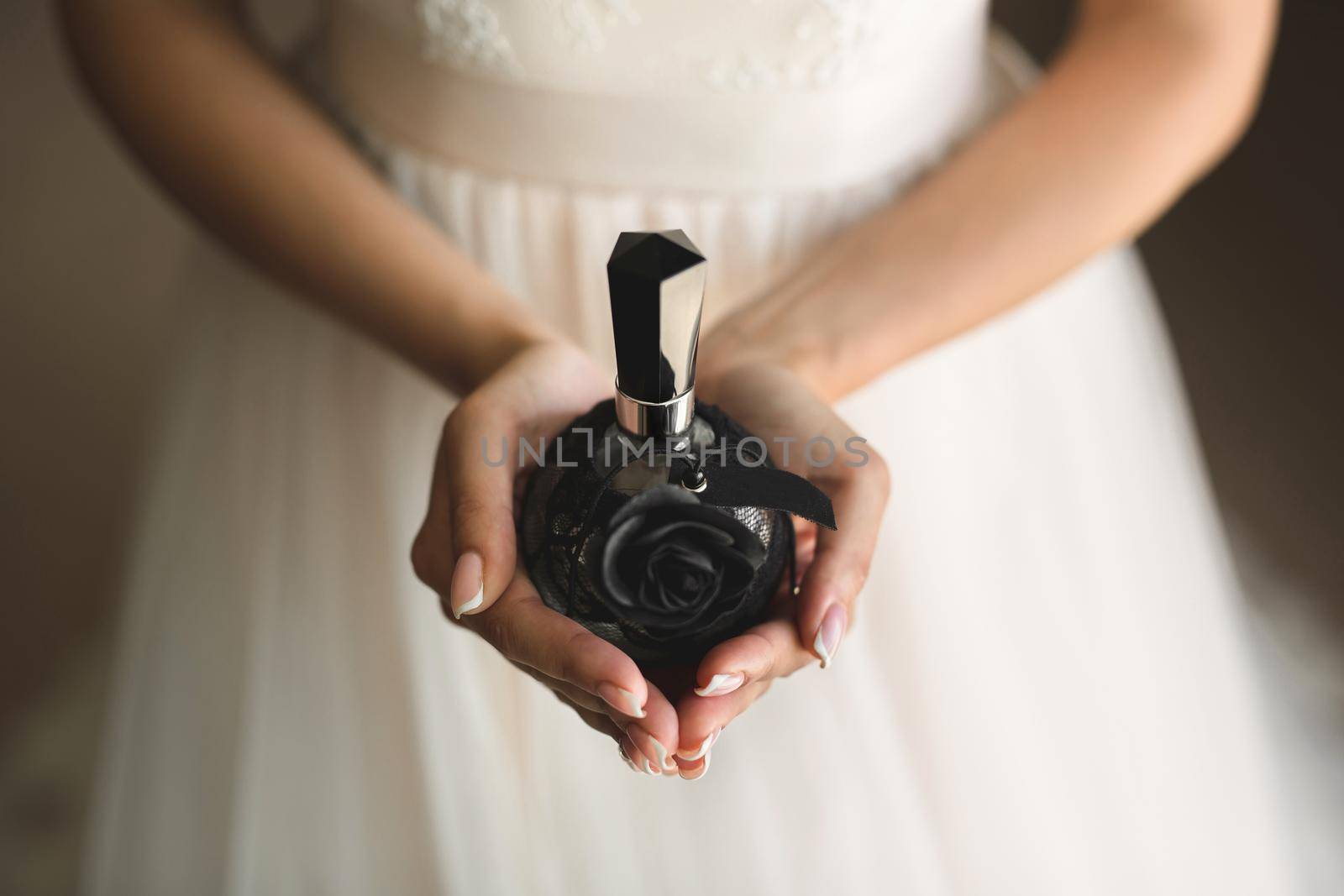 jar of perfume in the hands of the bride. Beautiful wedding manicure.Hands closeup. Wedding morning bride